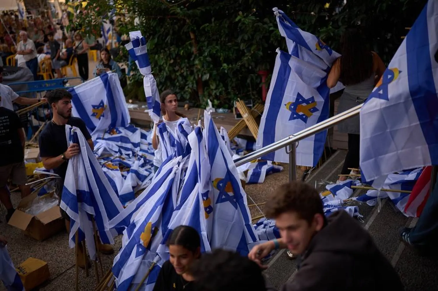  Volunteers prepare Israeli flags as people gather at a plaza known as hostages square, in Tel Aviv, Israel, Sunday, Oct. 12, 2025. (AP) 
