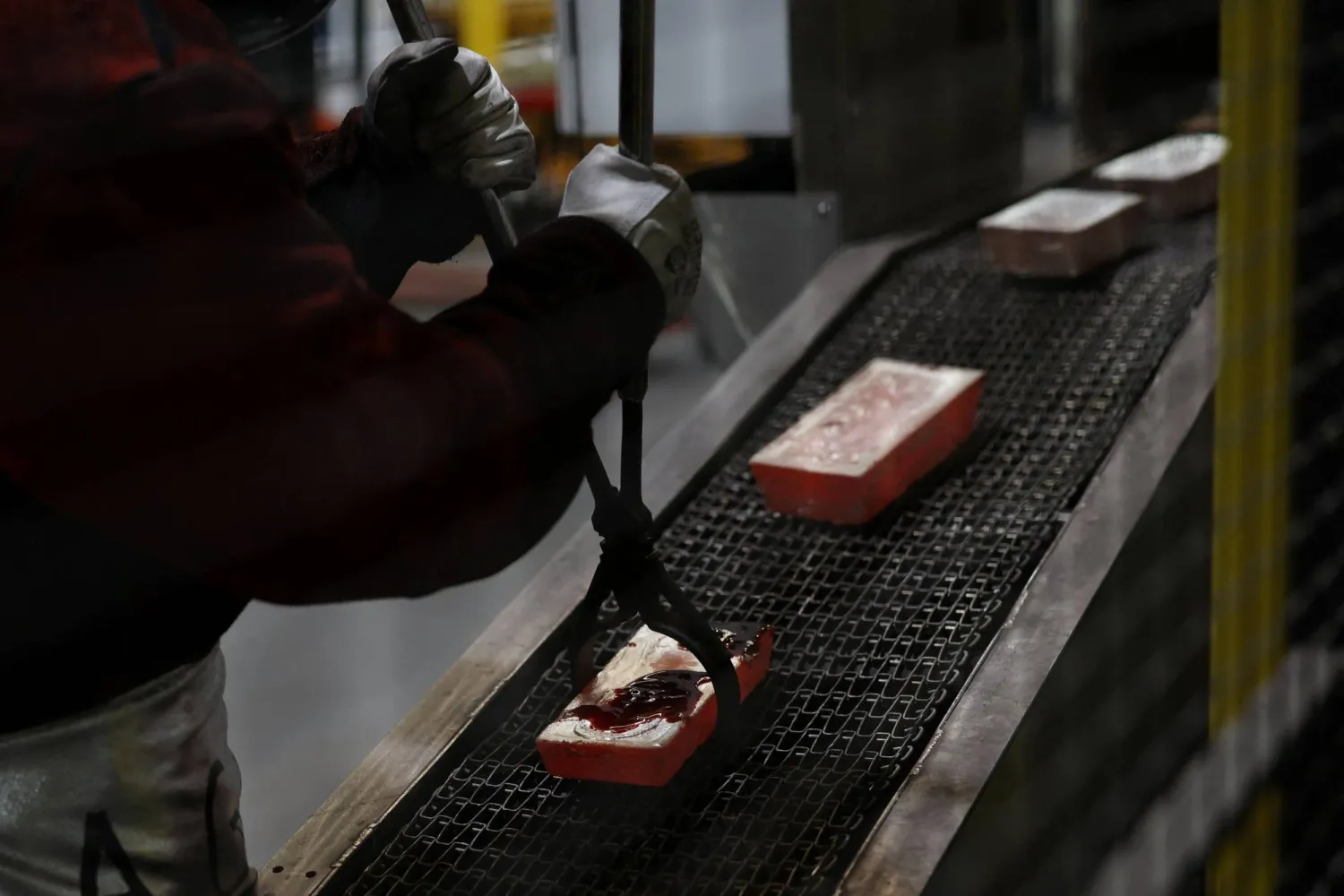 A worker places a gold brick on a conveyor belt during production at ABC Refinery in Sydney, Australia, October 13, 2025. REUTERS/Hollie Adams