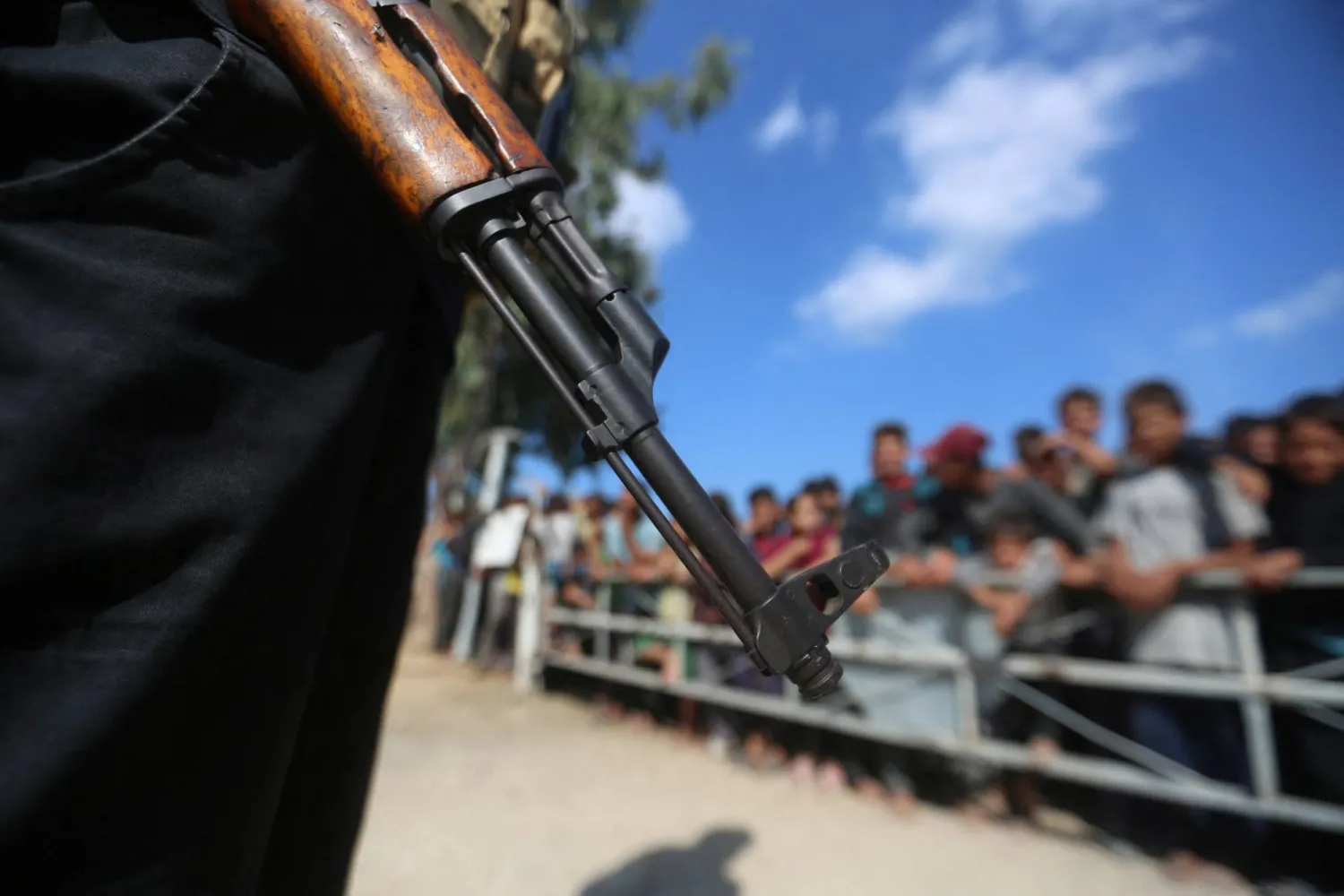 أحد عناصر «حماس» يقف حارساً ممسكاً ببندقية في حين تنقل مركبات الصليب الأحمر الرهائن المحتجزين في غزة (رويترز)