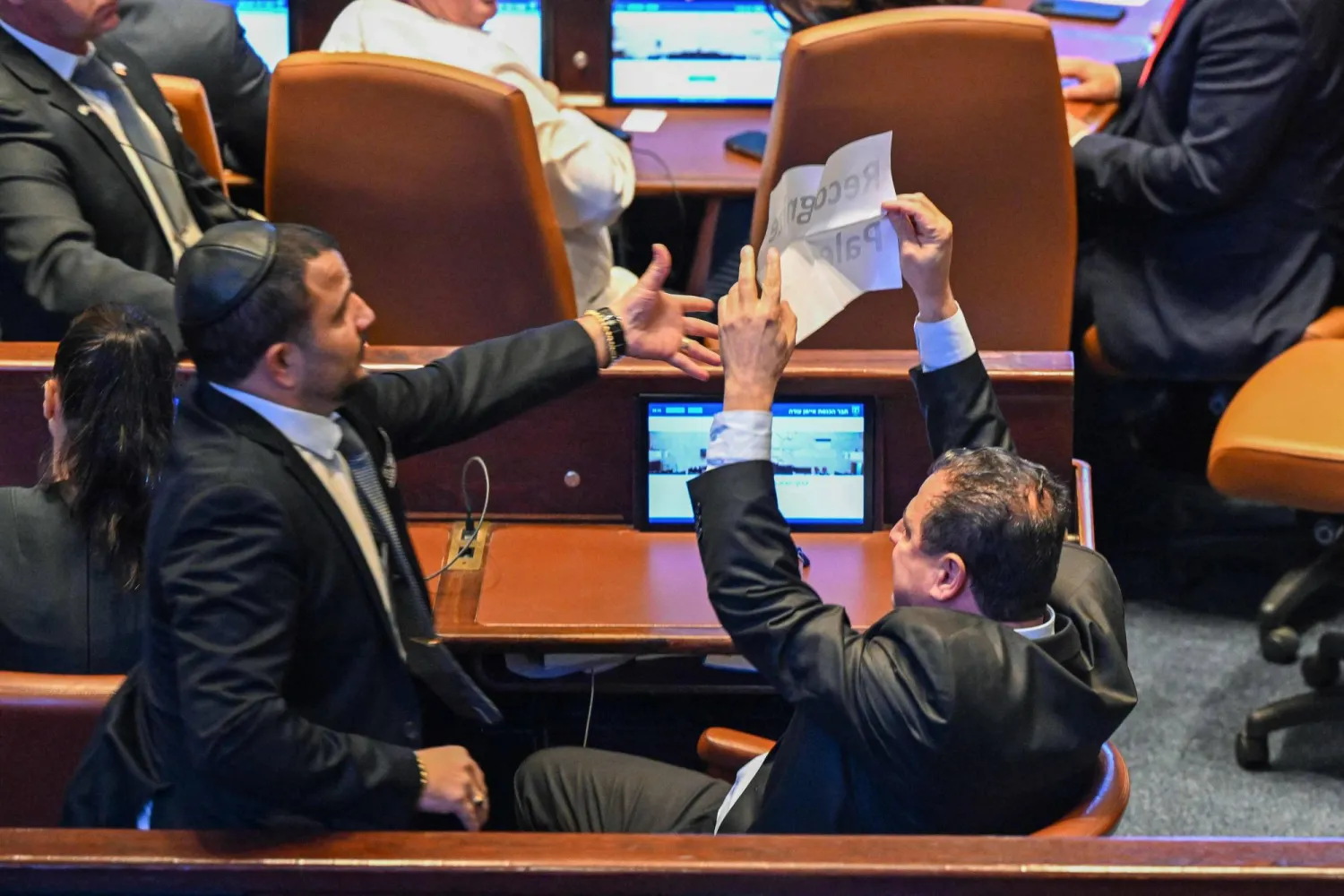 عضو الكنيست الإسرائيلي أيمن عودة (يمين) يحمل لافتة كُتب عليها «اعترفوا بفلسطين» خلال خطاب الرئيس الأميركي (أ.ف.ب)