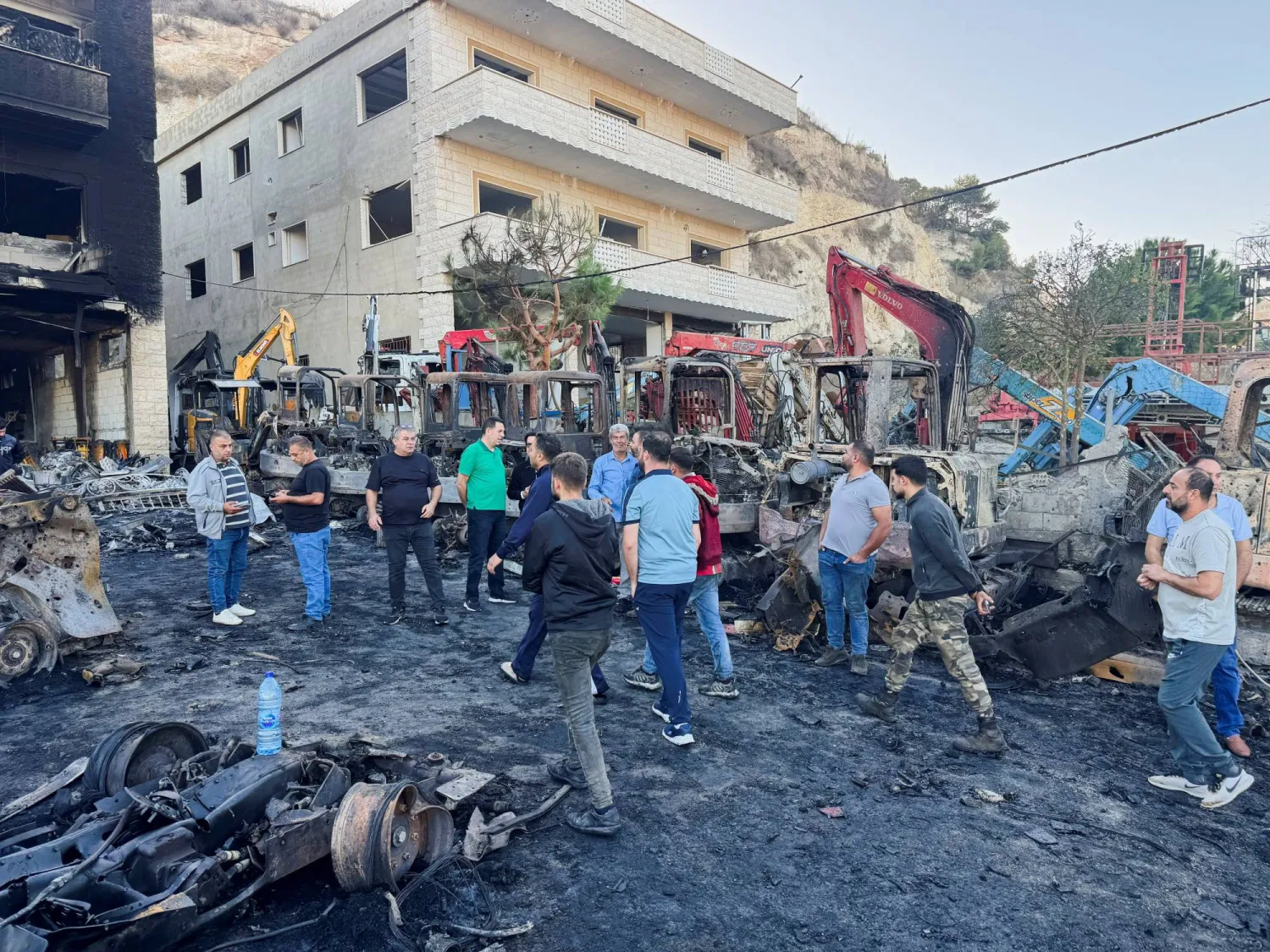 لبنانيون يتفقدون آثار القصف لمعارض بيع آليات ثقيلة بجنوب لبنان (رويترز)