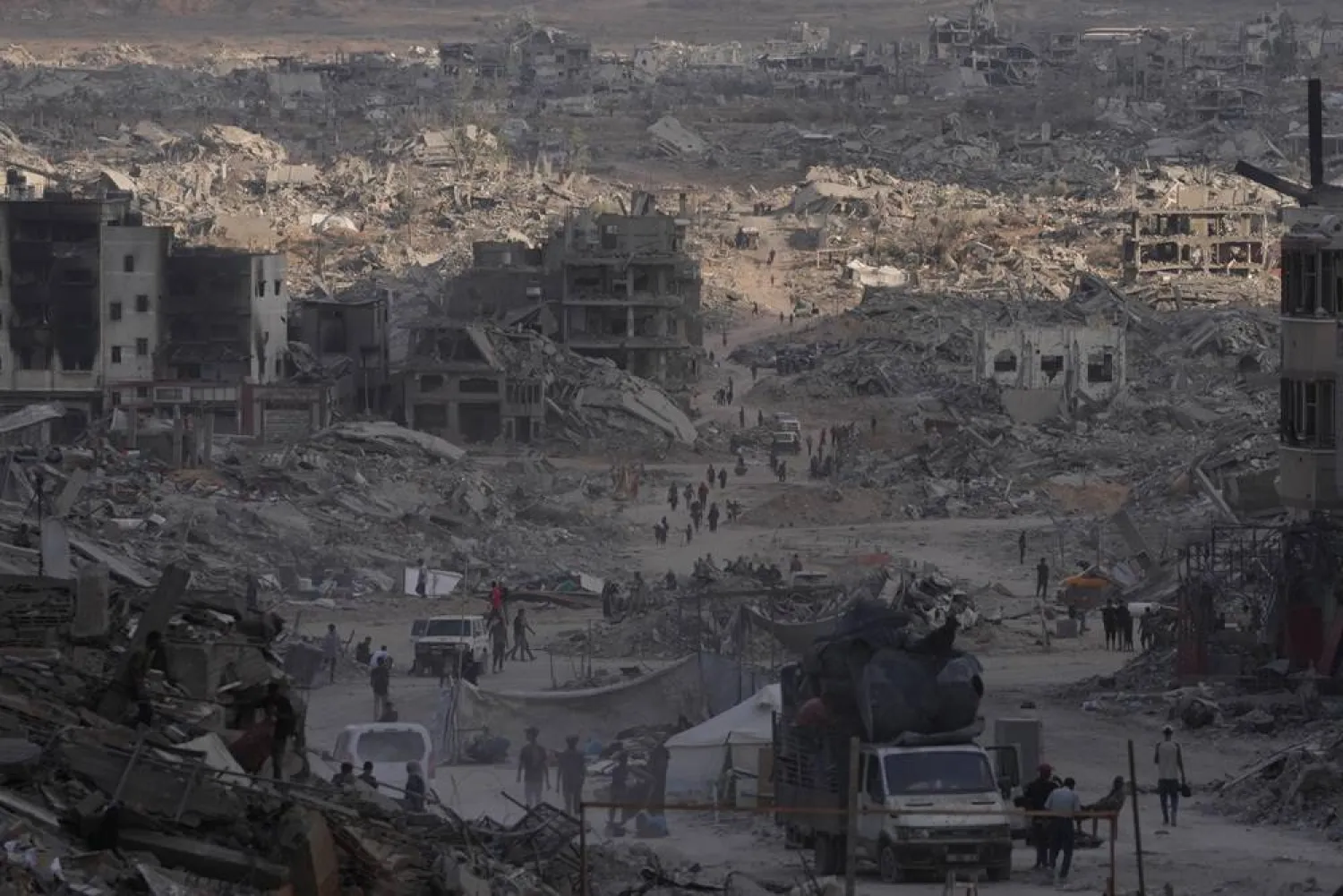  Palestinians walk among destroyed buildings in Gaza City, Sunday, Oct. 12, 2025, after Israel and Hamas agreed to a pause in their war and the release of the remaining hostages. (AP)