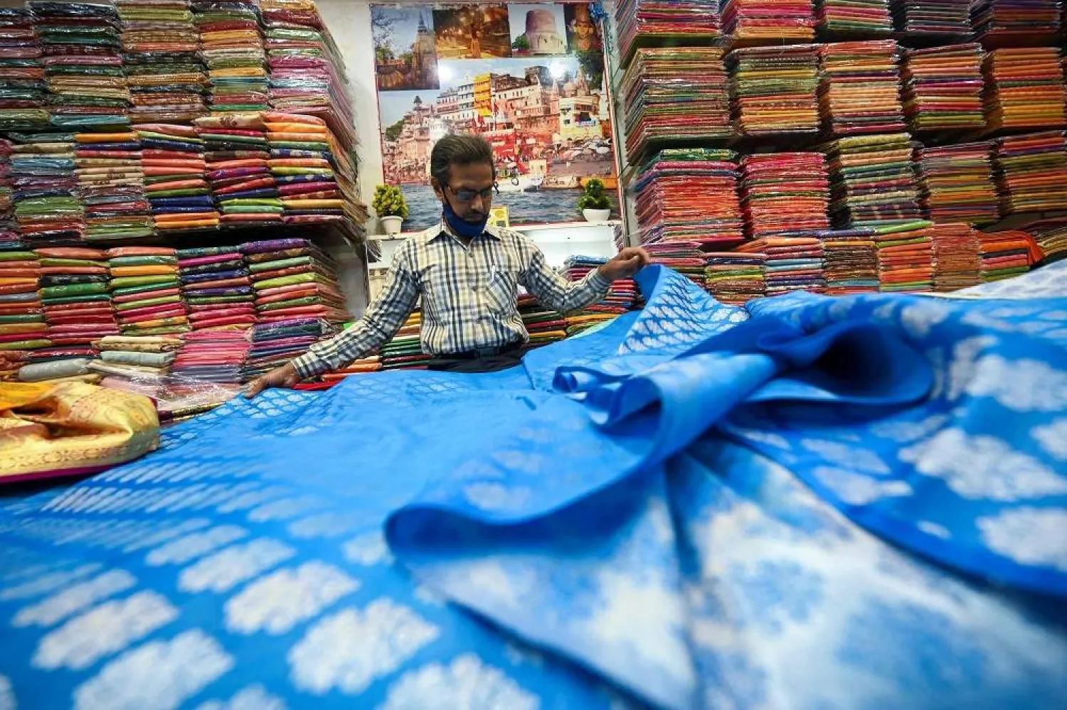 A shopkeeper shows a traditional Banarasi sari at a store in Varanasi on November 20, 2021. (AFP)