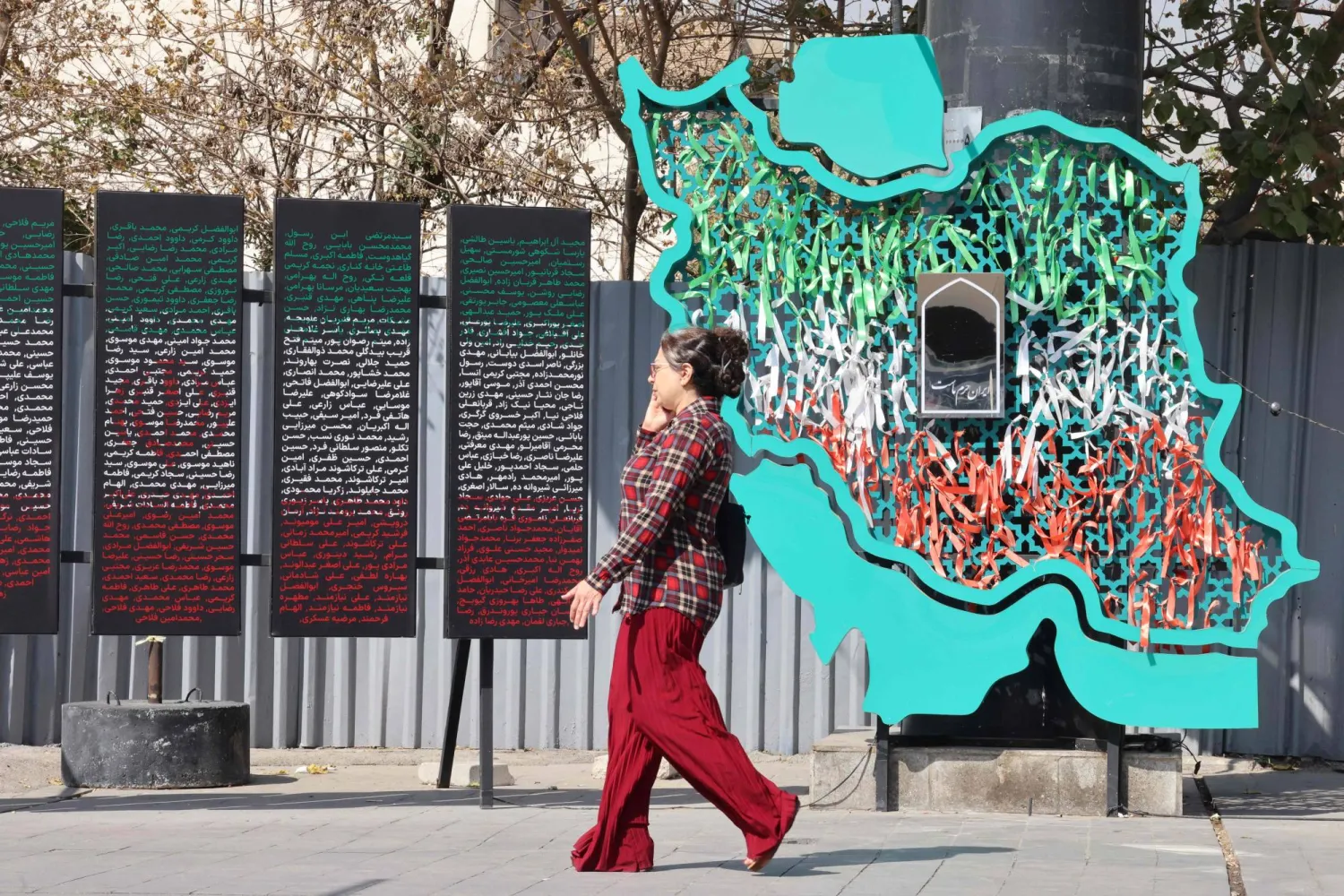 An Iranian woman walks past a map of Iran in Tehran on October 13, 2025. (AFP)