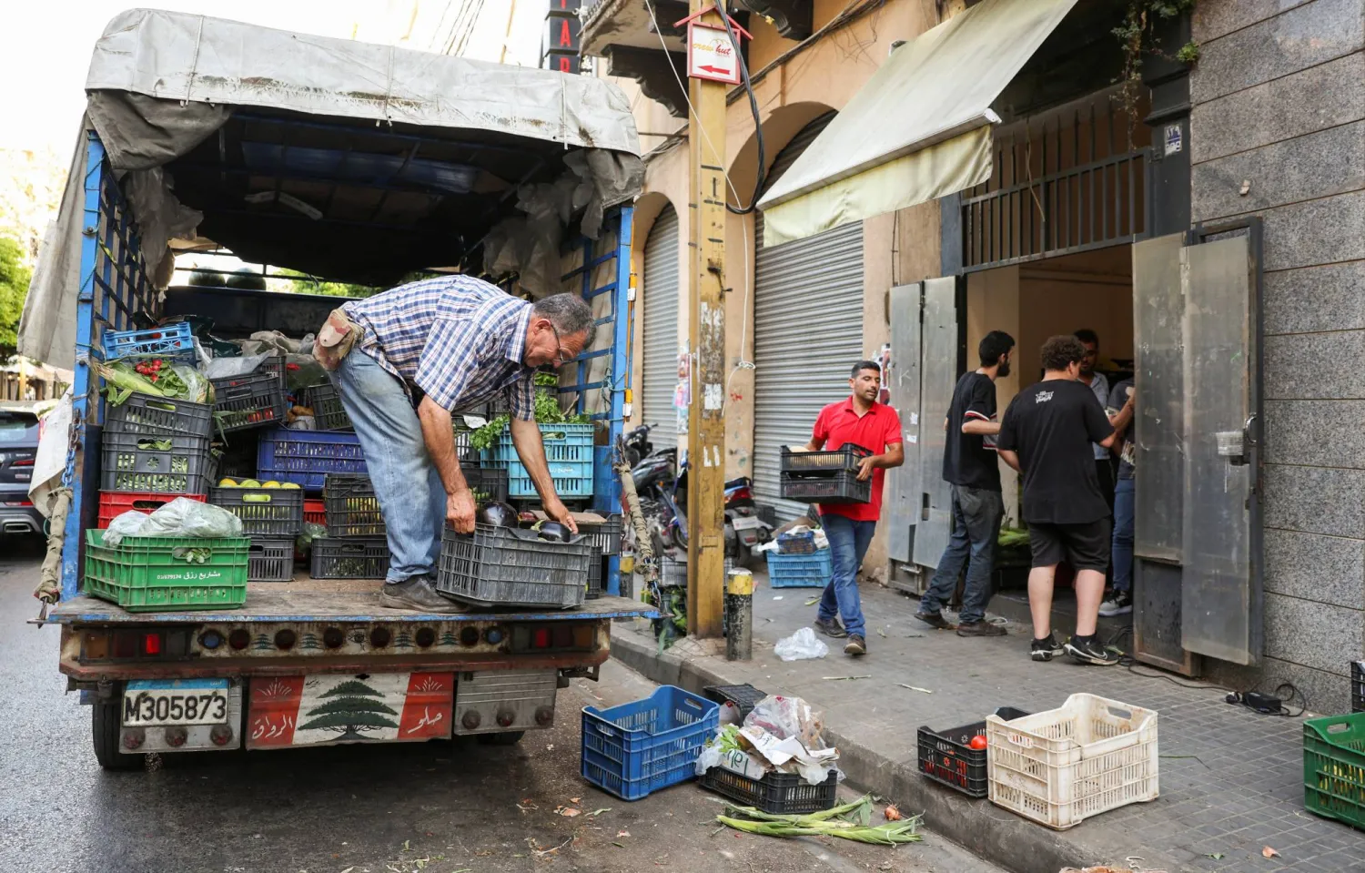 رجل يفرغ حمولة الخضراوات والفواكه من شاحنة في أحد أحياء بيروت (رويترز)