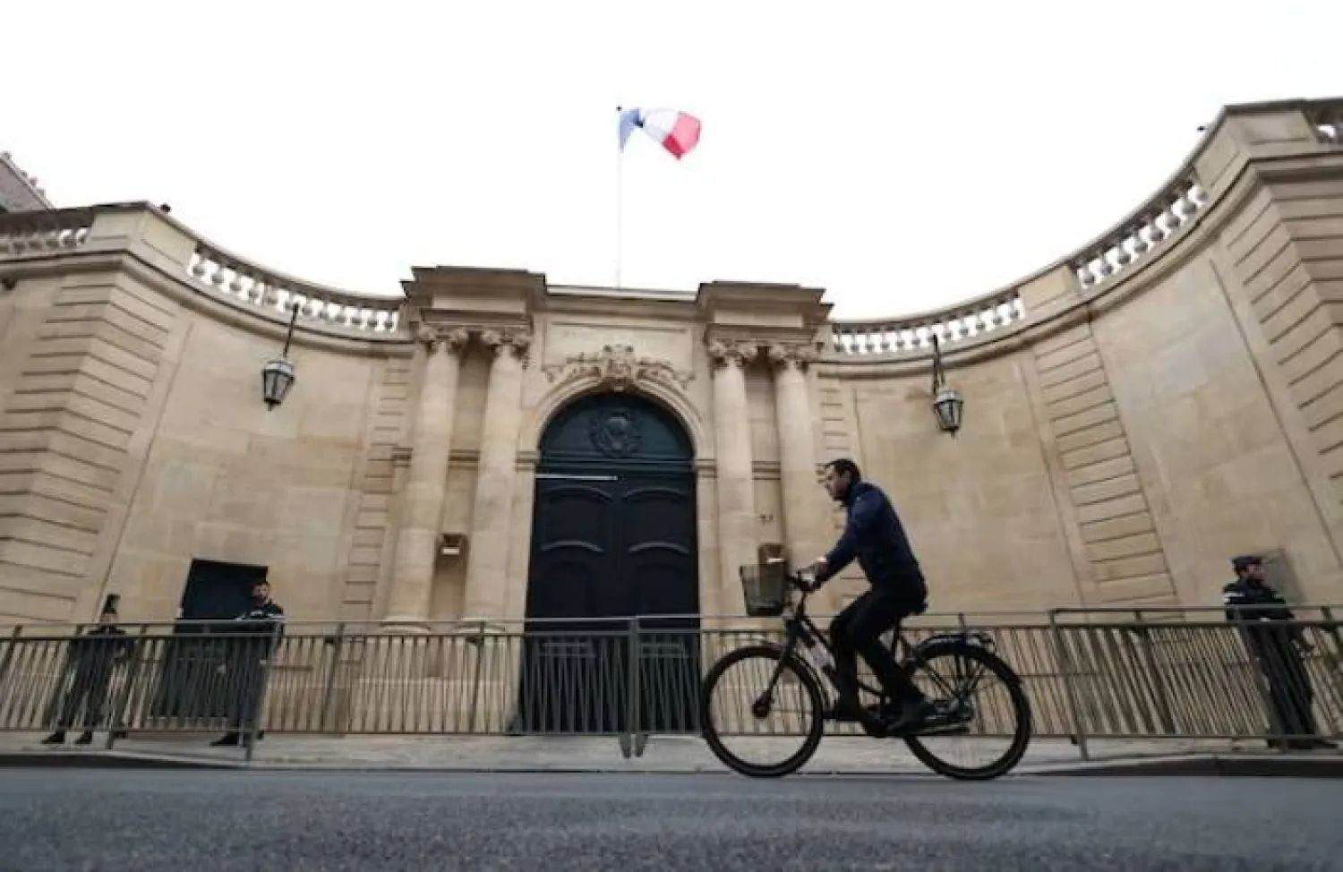 رجل يقود دراجته الهوائية أمام فندق «ماتينيون» في باريس (رويترز)