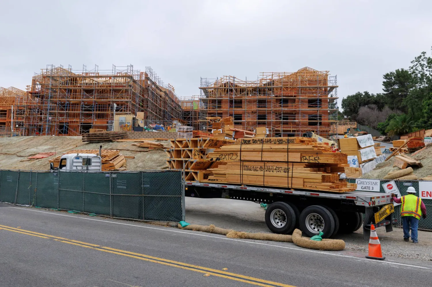 عامل بناء ينقل الخشب الخاص ببناء في كاليفورنيا (رويترز)