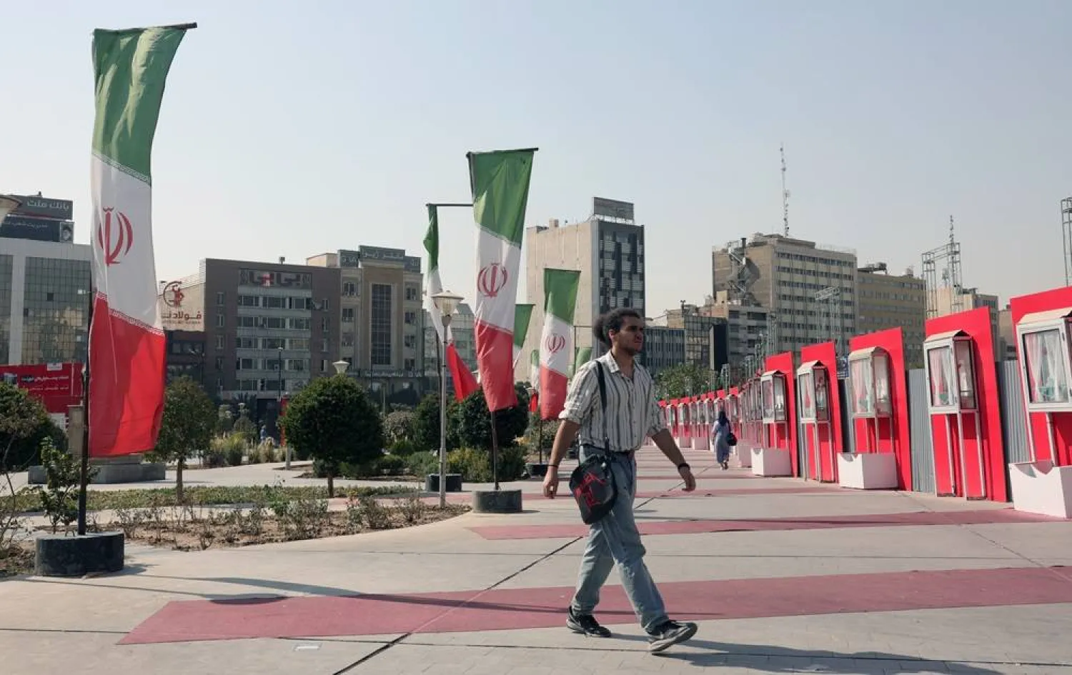 An Iranian man walks next to Iran's national flags on a street in Tehran, Iran, 13 October 2025. (EPA)