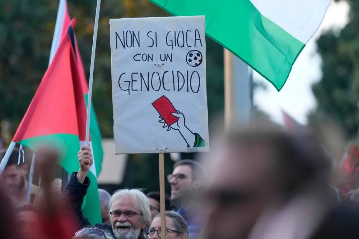  People hold a banner reading "you don't play with genocide" as they protest against the participation of the Israeli national team in the 2026 Soccer World Cup qualification match against Italy being played in the evening in Udine, Italy, Tuesday, Oct. 14, 2025. (AP)