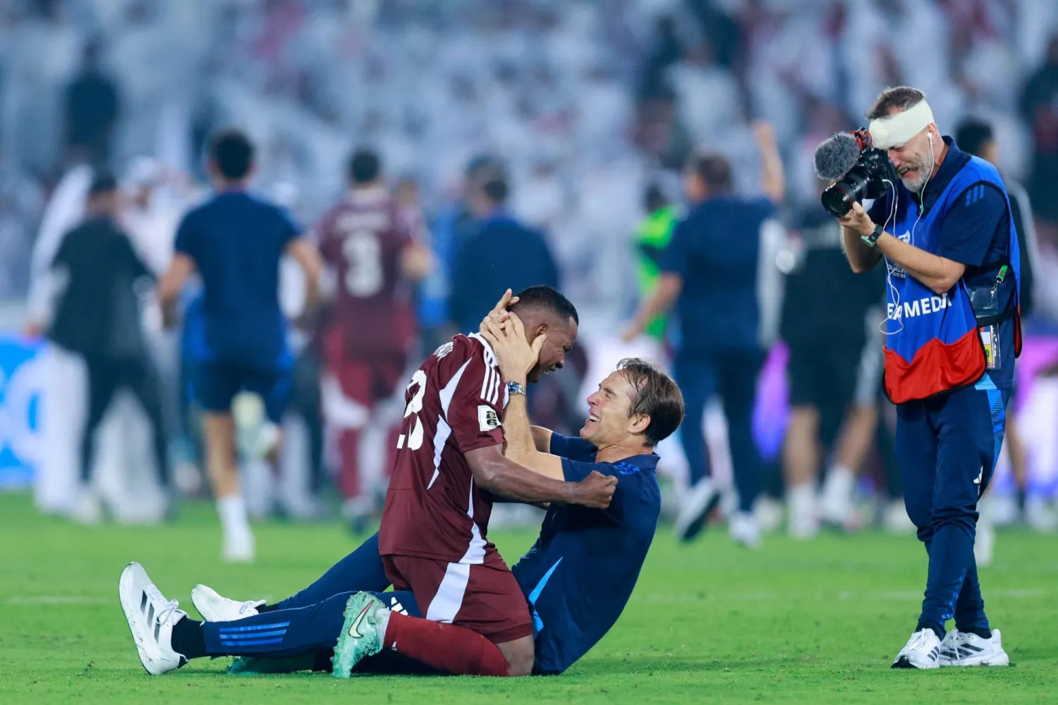 عاصم ماديبو لاعب قطر يحتفل مع مدربه الإسباني خولن لوبيتيغي بالتأهل للمونديال (أ.ف.ب)