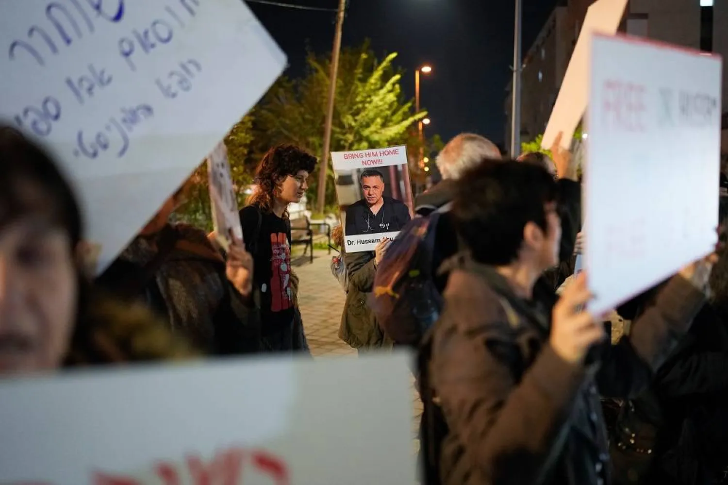 A woman holds a sign with a photo of Palestinian Dr. Hussam Abu Safiya during a protest calling for his release in front of the Shin Bet offices in Tel Aviv, Israel, Jan. 1, 2025. (AP) 