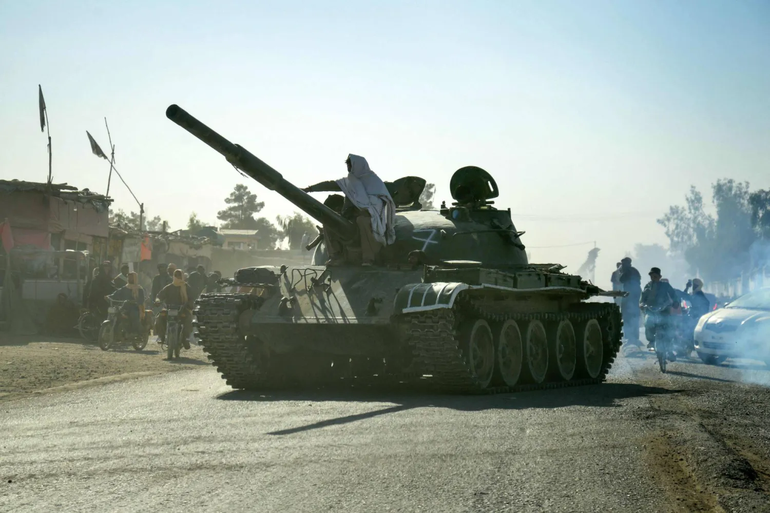 Taliban security personnel on a Soviet-era tank are followed by motorcyclists as they ride towards the border, as clashes take place between Taliban security personnel and Pakistani border forces, in the Spin Boldak district of Kandahar Province on October 15, 2025. (AFP)
