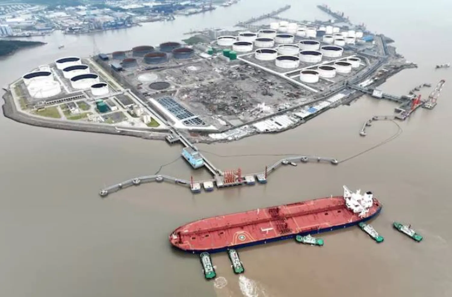 زوارق سحب تساعد ناقلة نفط خام على الرسو في محطة نفطية قبالة جزيرة ويدياو في تشوشان بمقاطعة تشجيانغ (رويترز)