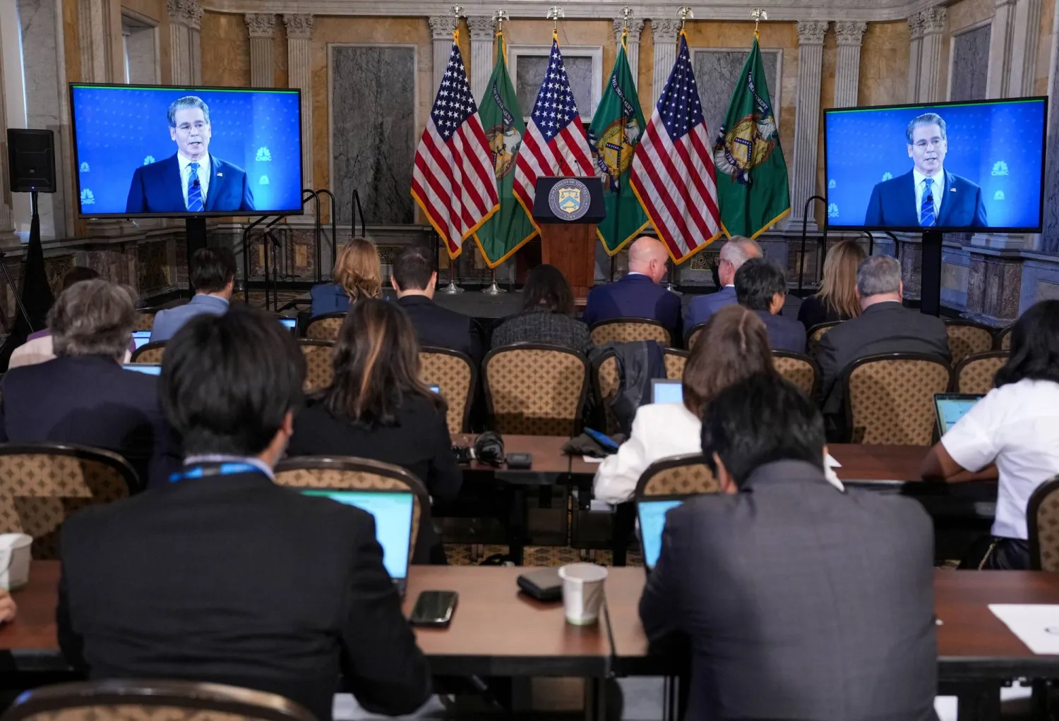 وزير الخزانة الأميركي سكوت بيسنت يظهر على الشاشة في المركز الإعلامي بمقر صندوق النقد الدولي في واشنطن (رويترز)