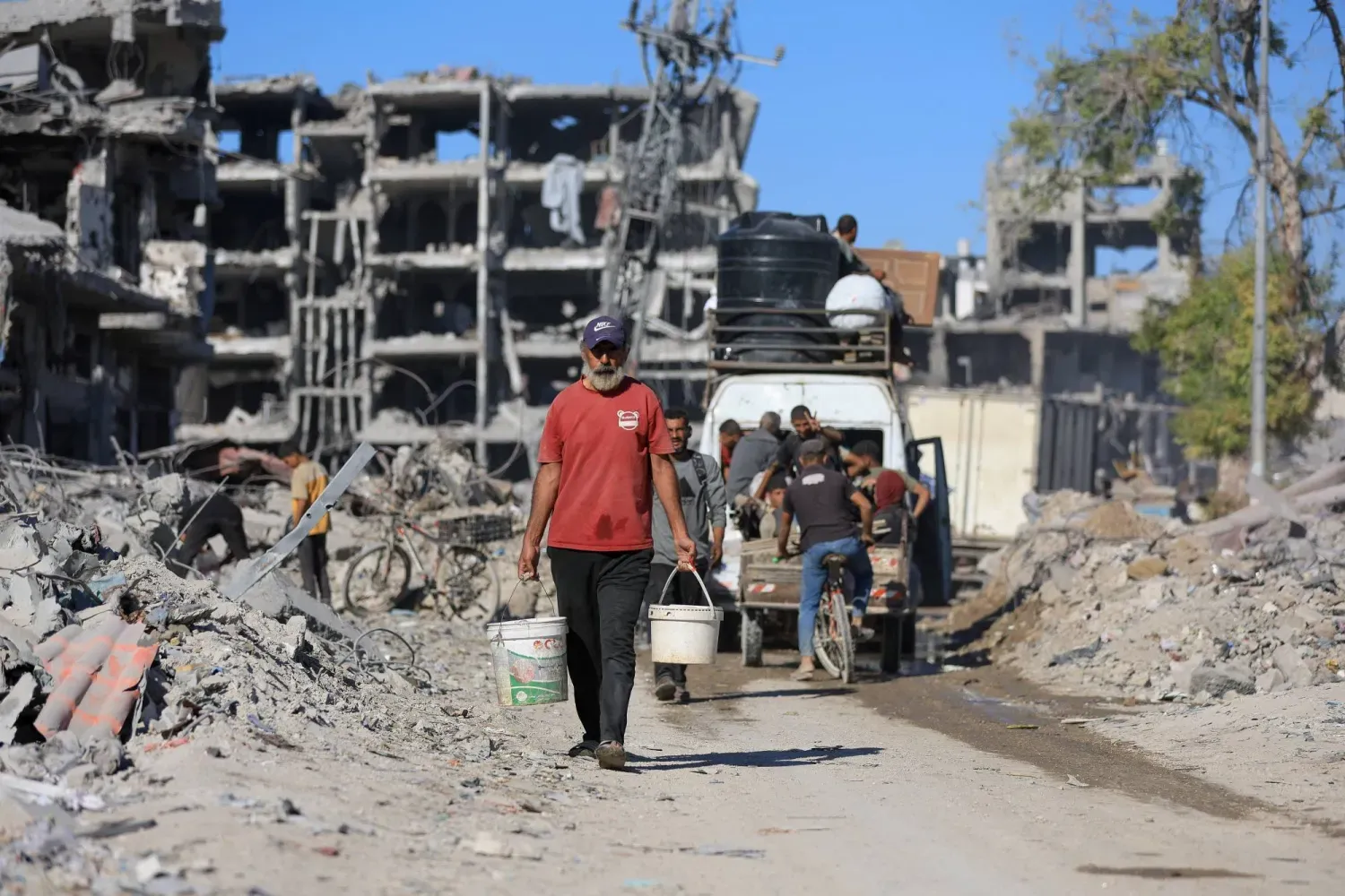 Filistinliler, 14 Ekim 2025'te Gazze Şehri'nde İsrail ile Hamas arasındaki ateşkes sırasında yıkılmış binaların enkazının arasından geçiyor. (Reuters)