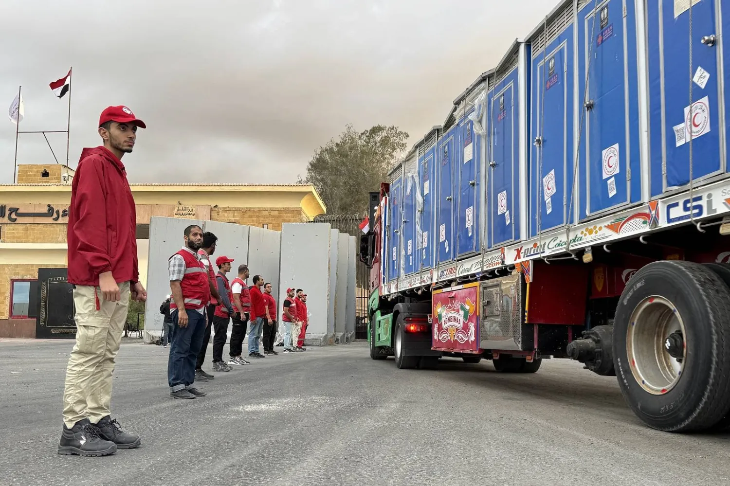 أعضاء من «الهلال الأحمر المصري» قرب شاحنة محملة بالمساعدات الإنسانية أمام معبر رفح (أ.ف.ب)