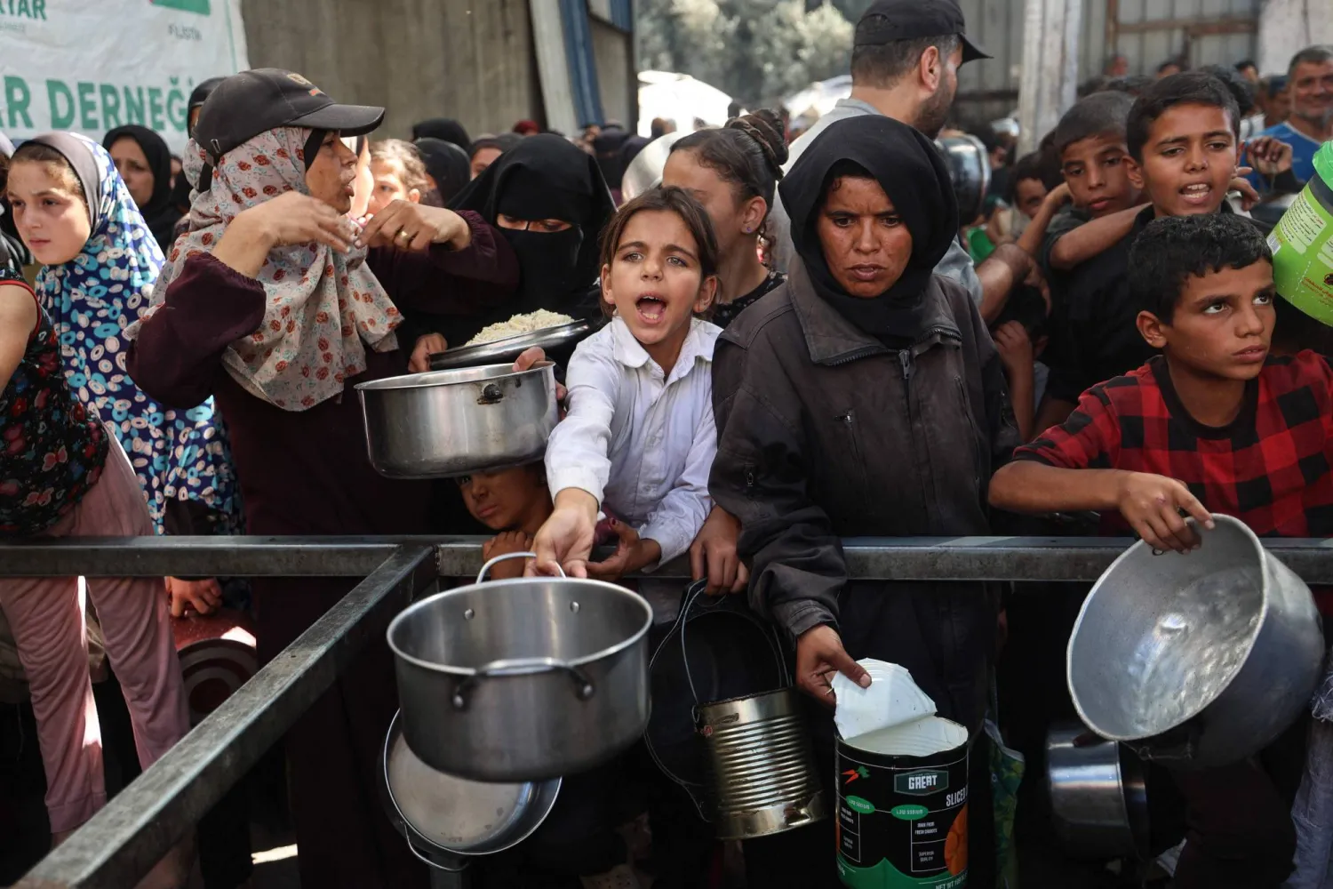 فلسطينيون يتجمعون لتسلم حصص غذائية من مطبخ خيري في مخيم النصيرات للاجئين وسط قطاع غزة (أ.ف.ب)