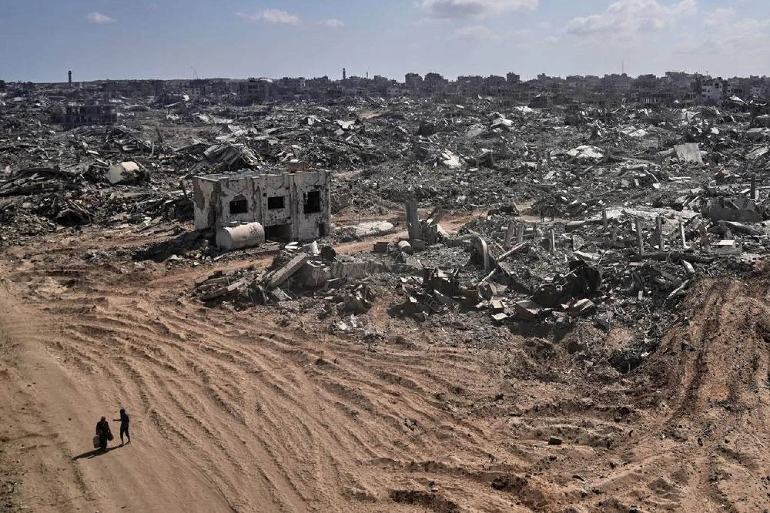  Two displaced Palestinians walk past destroyed buildings in the heavily damaged Sheikh Radwan neighborhood in Gaza City, Saturday, Oct. 11, 2025, after Israel and Hamas agreed to a pause in their war and the release of the remaining hostages. (AP)