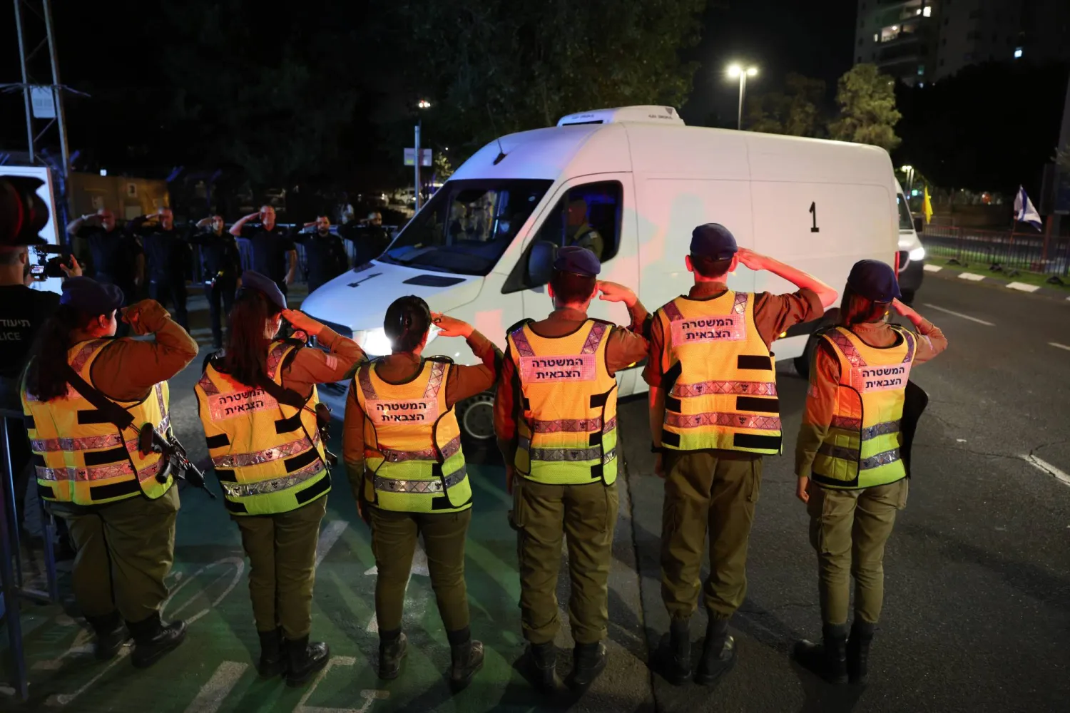 جنود إسرائيليون يؤدون التحية العسكرية لدى وصول قافلة تحمل جثتَي رهينتين سلّمتهما «حماس» إلى المركز الوطني للطب الشرعي في تل أبيب (إ.ب.أ)