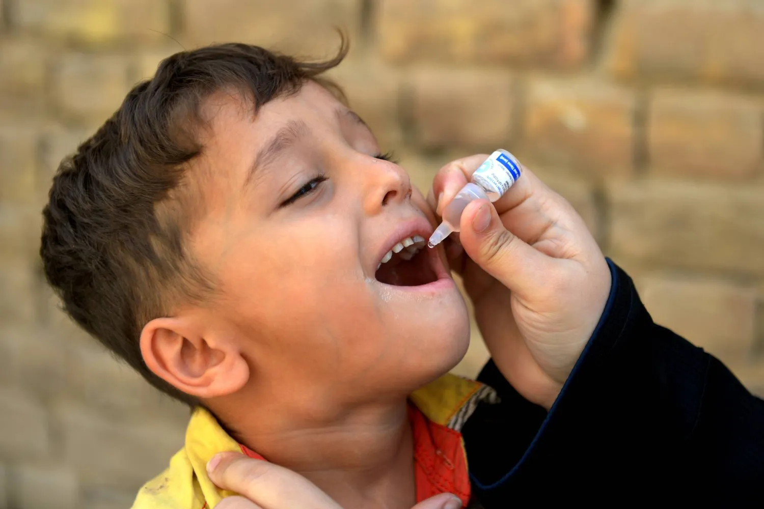 عامل رعاية صحية يُعطي جرعة من لقاح شلل الأطفال لطفل خلال حملة تطعيم في بيشاور بمقاطعة خيبر بختونخوا بباكستان يوم 13 أكتوبر 2025 (إ.ب.أ)