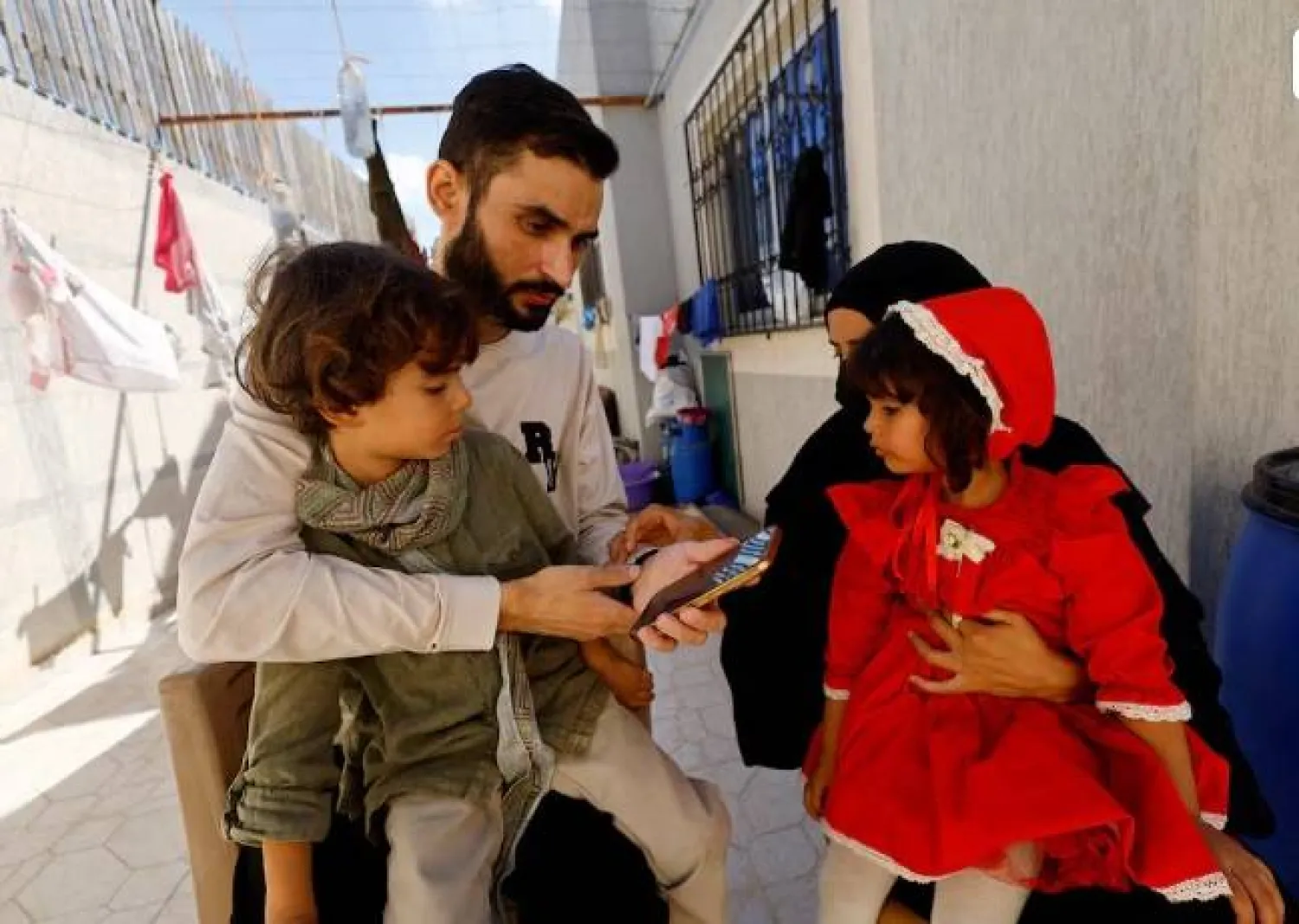 Freed Palestinian detainee Shadi Abu Sido sits with his wife Hanaa Bahlul and their children at their home in Nuseirat, central Gaza Strip, after he was released from Israeli detention as part of a ceasefire deal between Hamas and Israel, October 14, 2025. REUTERS/Mahmoud Issa Purchase Licensing Rights