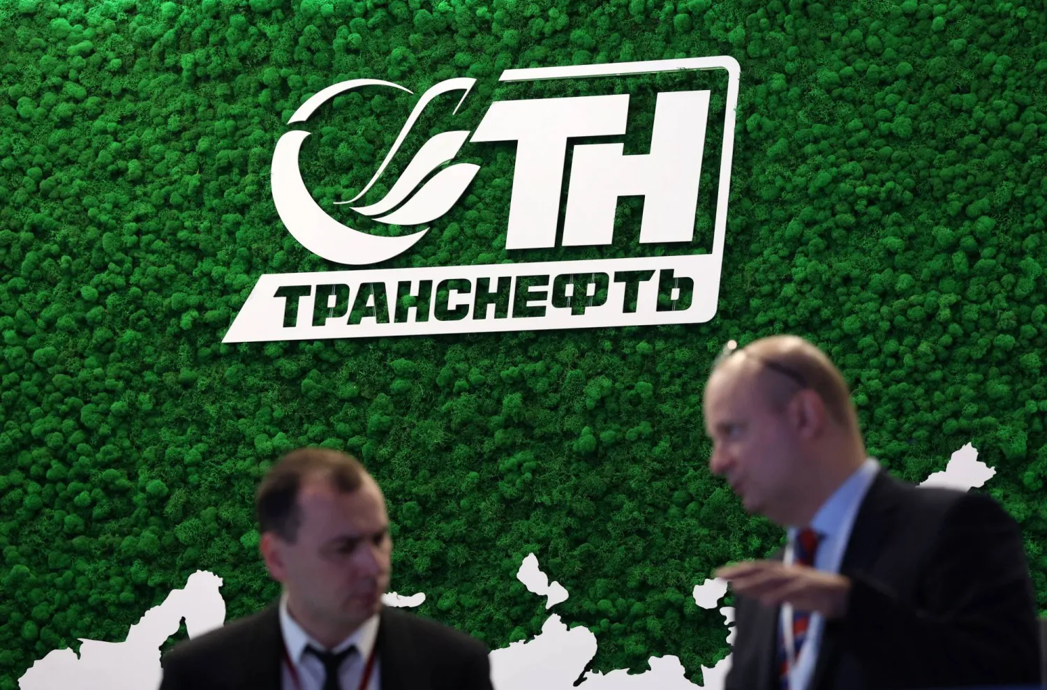 مشاركان في أسبوع الطاقة الروسي يتحدثان أمام جناح عرض لشركة «ترانسنفت» (رويترز)