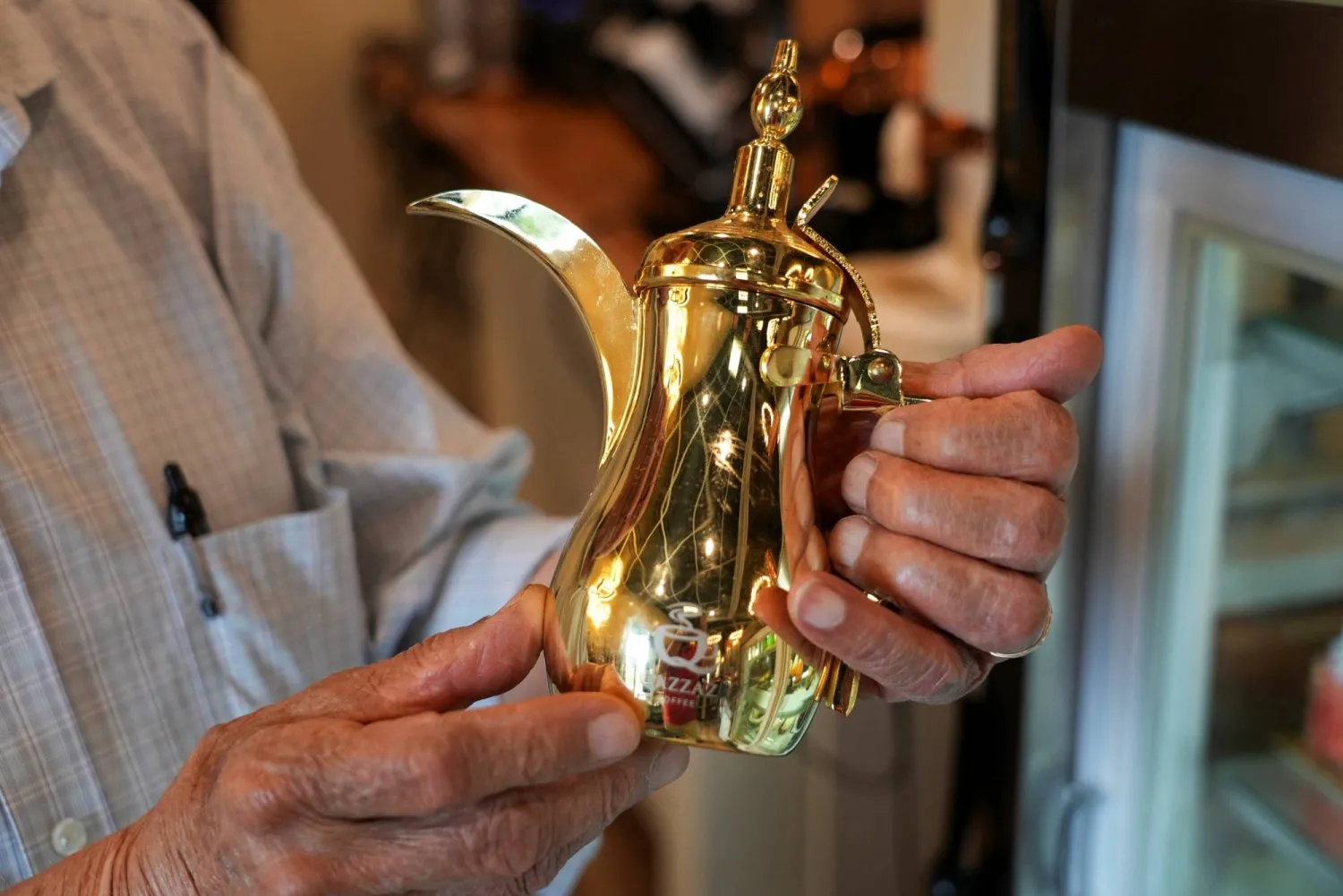 الفلسطيني أنور القزاز صاحب مقهى في ميتشيغن بالولايات المتحدة يمسك بدلة قهوة عربية (رويترز)