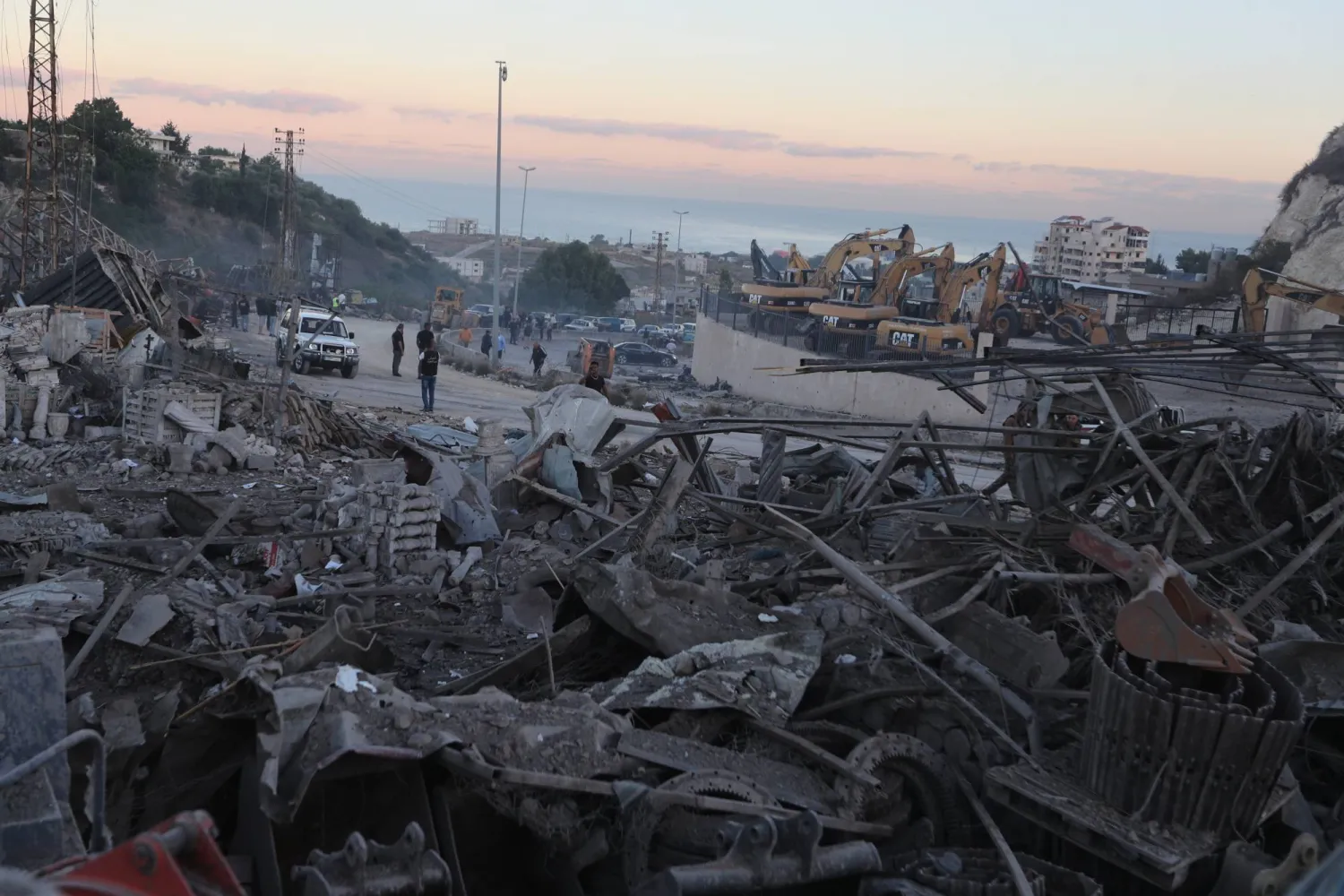 People gather at a site that sold heavy machinery, where a large number of vehicles were destroyed in Israeli airstrikes, in the southern village of Msayleh, Lebanon, Saturday, Oct. 11, 2025. (AP Photo/Mohammed Zaatari)