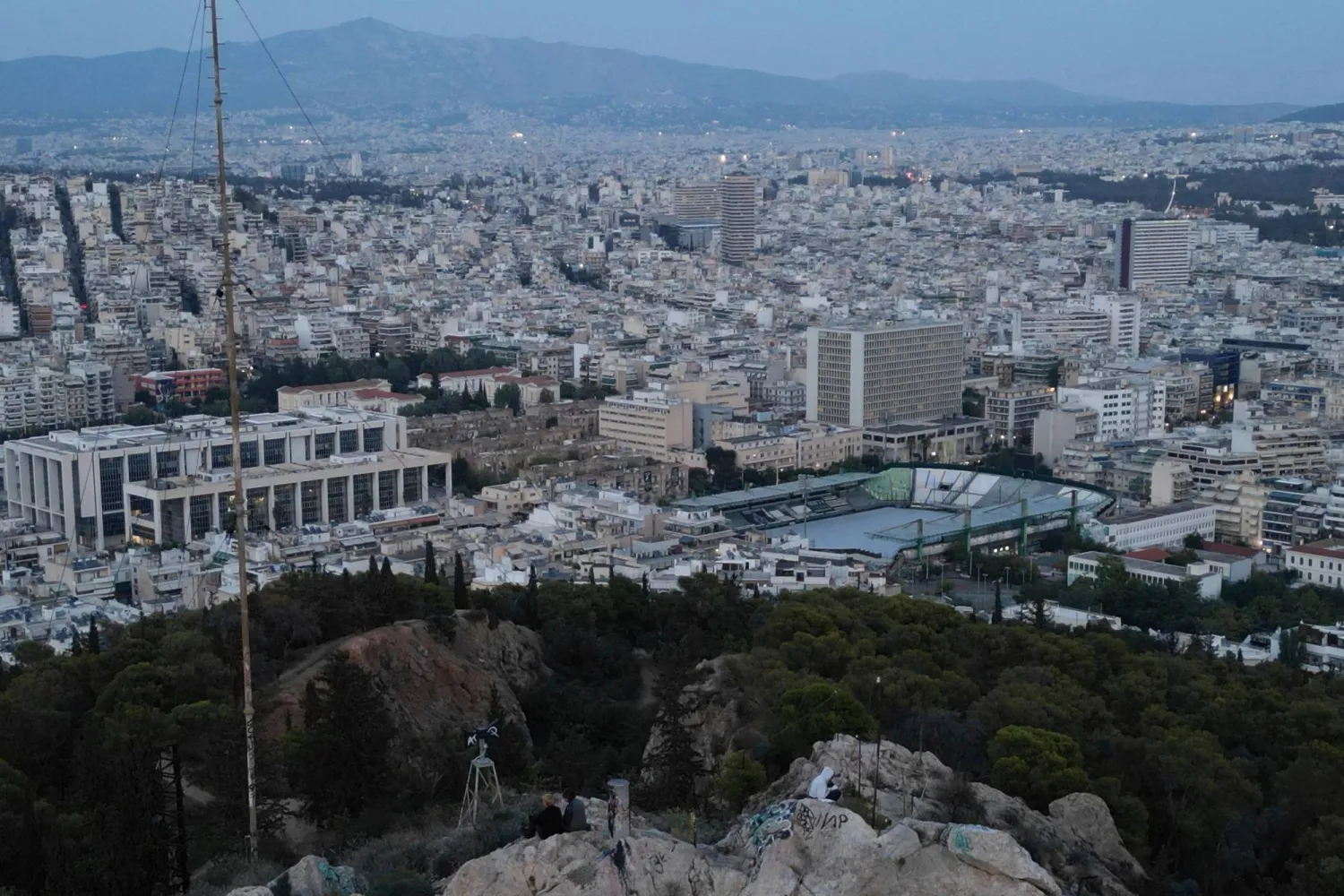 Youths sit on a rock on Lycabettus hill overlooking Athens, Greece, Wednesday, Oct. 15, 2025. (AP Photo/Thanassis Stavrakis)
