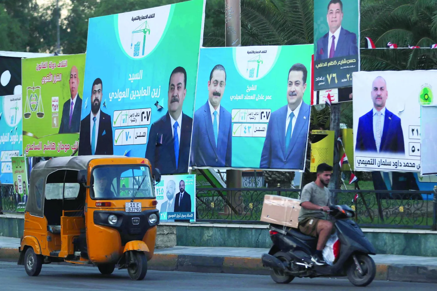 عراقيون يمرون بجانب لافتات انتخابية في أحد شوارع بغداد قبيل الانتخابات البرلمانية المقررة يوم 11 نوفمبر 2025 (أ.ف.ب)