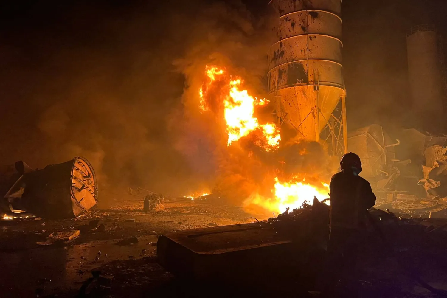 رجال إطفاء يشاركون في إخماد حرائق اندلعت في مصنع للإسمنت استهدفته غارات إسرائيلية بجنوب لبنان (أ.ف.ب)