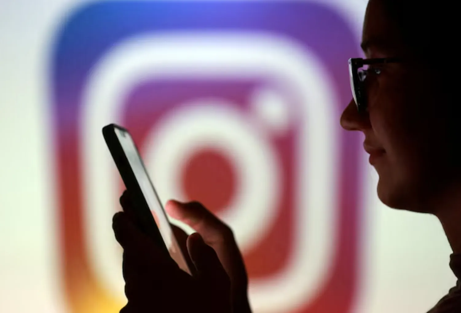 A teenager poses for a photo while holding a smartphone in front of a Instagram logo in this illustration taken September 11, 2025. REUTERS/Dado Ruvic/Illustration/File Photo 