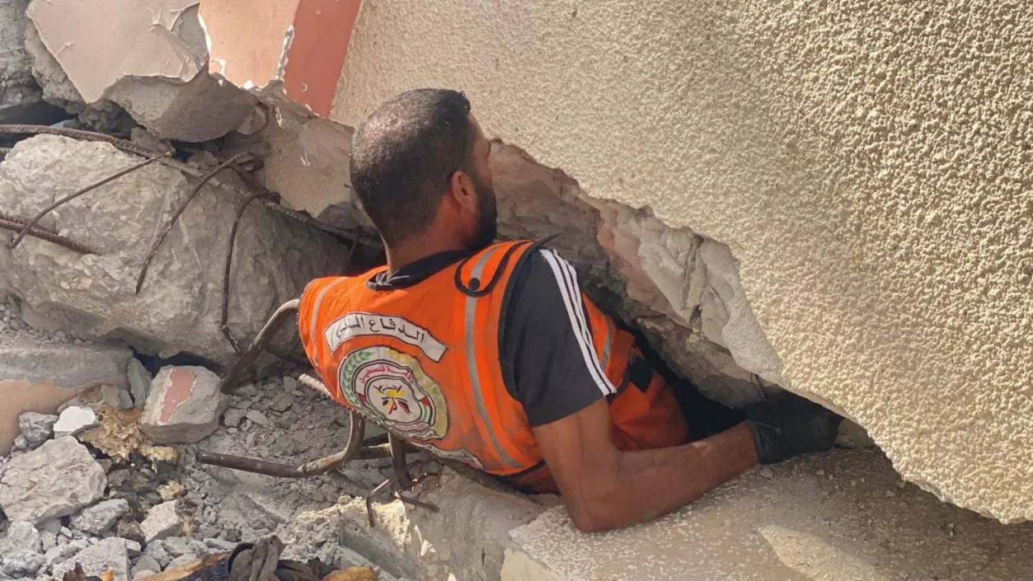 أحد عناصر الدفاع المدني الفلسطيني خلال عملية إنقاذ عالقين أسفل عقار خلال الهجمات الإسرائيلية على غزة (الدفاع المدني الفلسطيني)