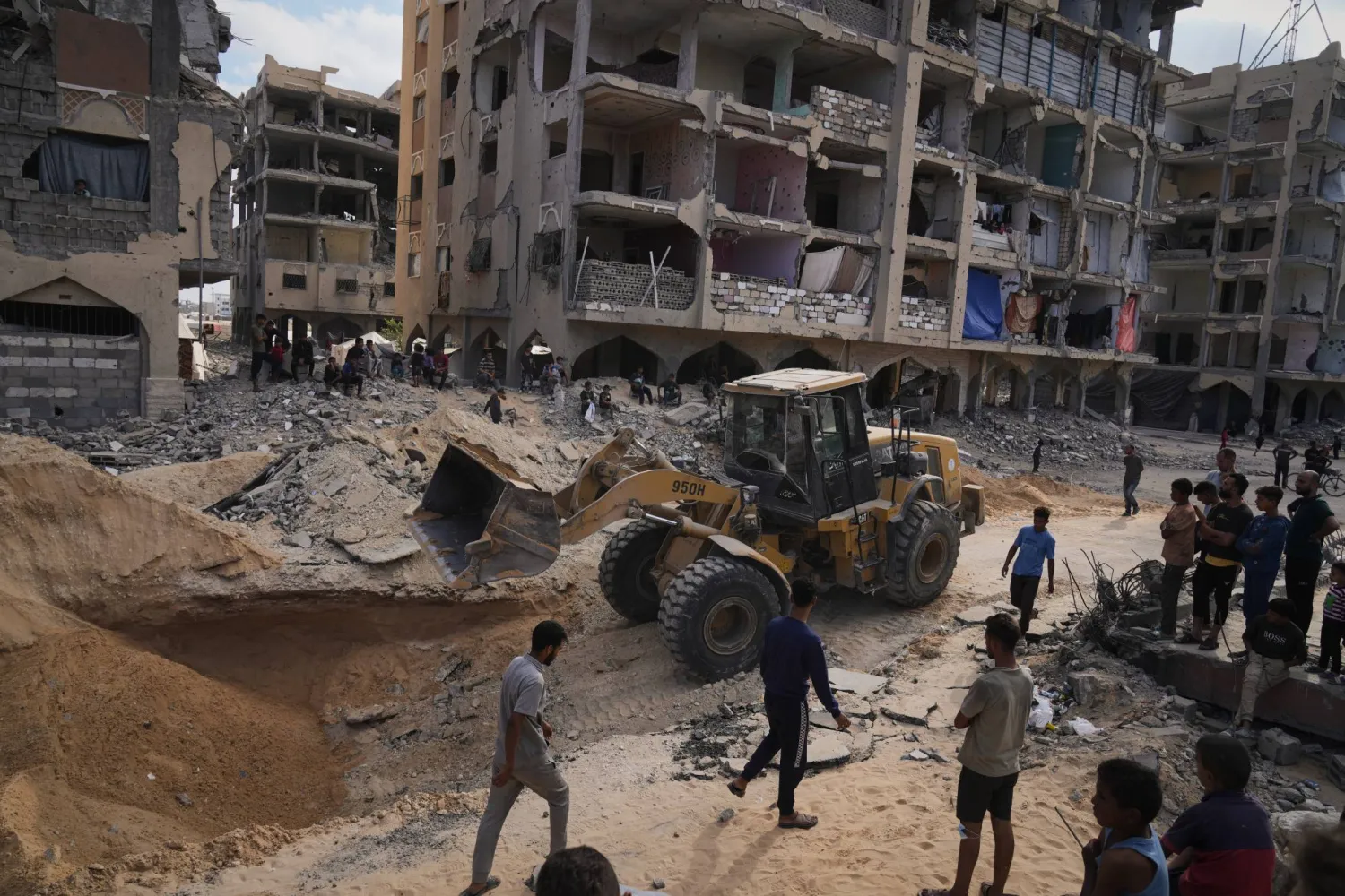 فلسطينيون يراقبون أعضاء من حركة «حماس» وهم يبحثون عن جثث الرهائن في منطقة بمدينة حمد في خان يونس (أ.ب)