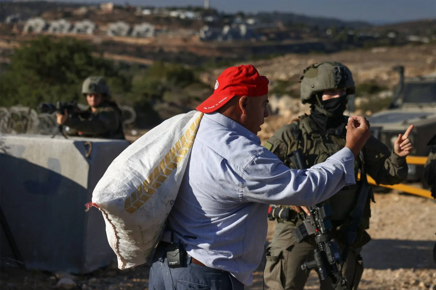 قوات الأمن الإسرائيلية تمنع رجلاً فلسطينياً من الوصول إلى أرضه لقطف الزيتون في قرية كوبر بالقرب من رام الله (أ.ف.ب)