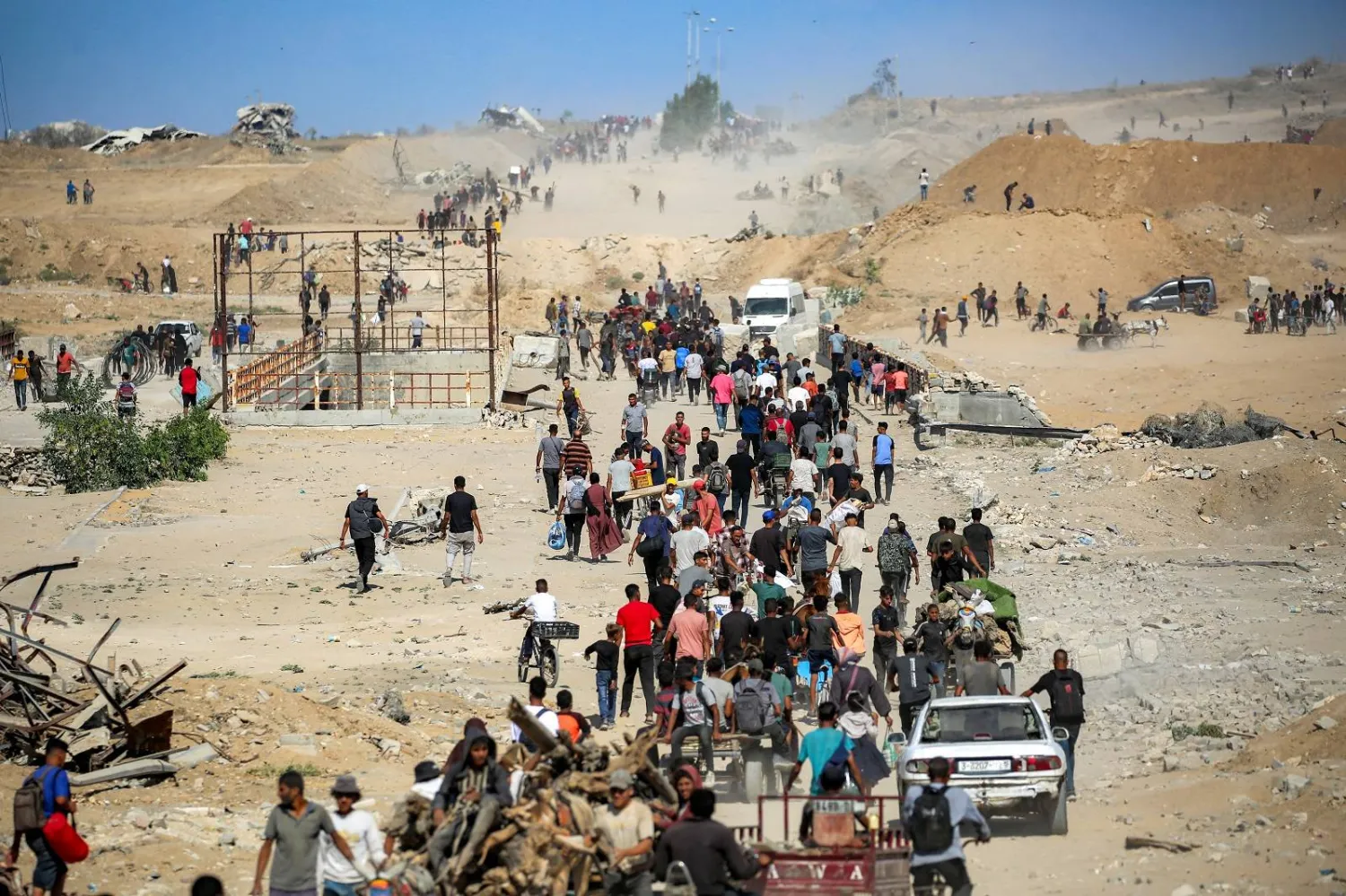 أشخاص يشقون طريقهم عبر ممر نتساريم بالقرب من النصيرات وسط قطاع غزة (أ.ف.ب)