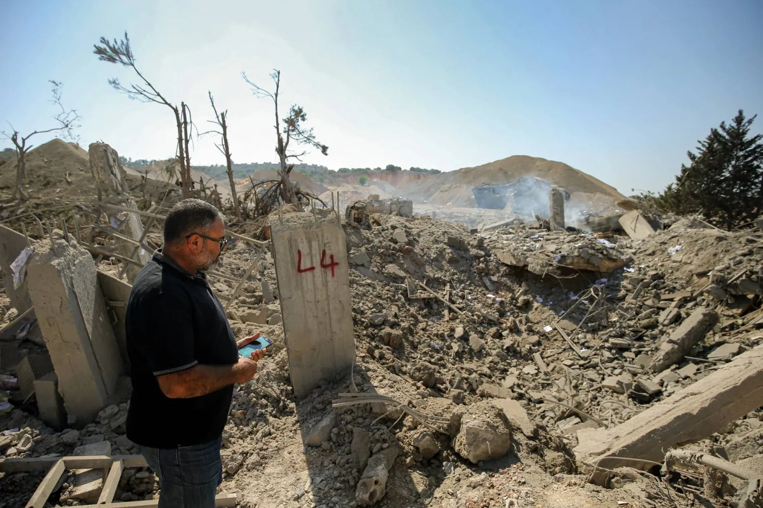 لبناني يقف بجوار حفرة تسبب فيها قصف إسرائيلي على بلدة أنصار بجنوب لبنان (د.ب.أ) 