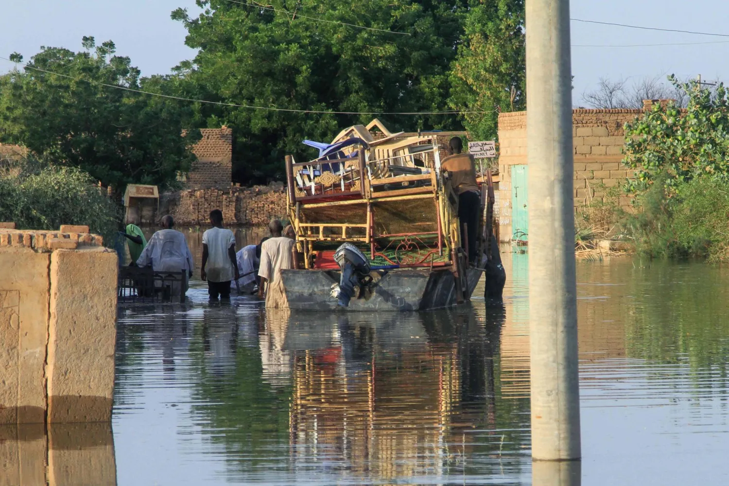 Residents use a barge to transport belongings as water drowns a road and the surrounding area due to the flooding of the Nile river in the Sudanese village of Wad Ramli north of Khartoum on October 1, 2025. (Photo by Ebrahim Hamid / AFP)