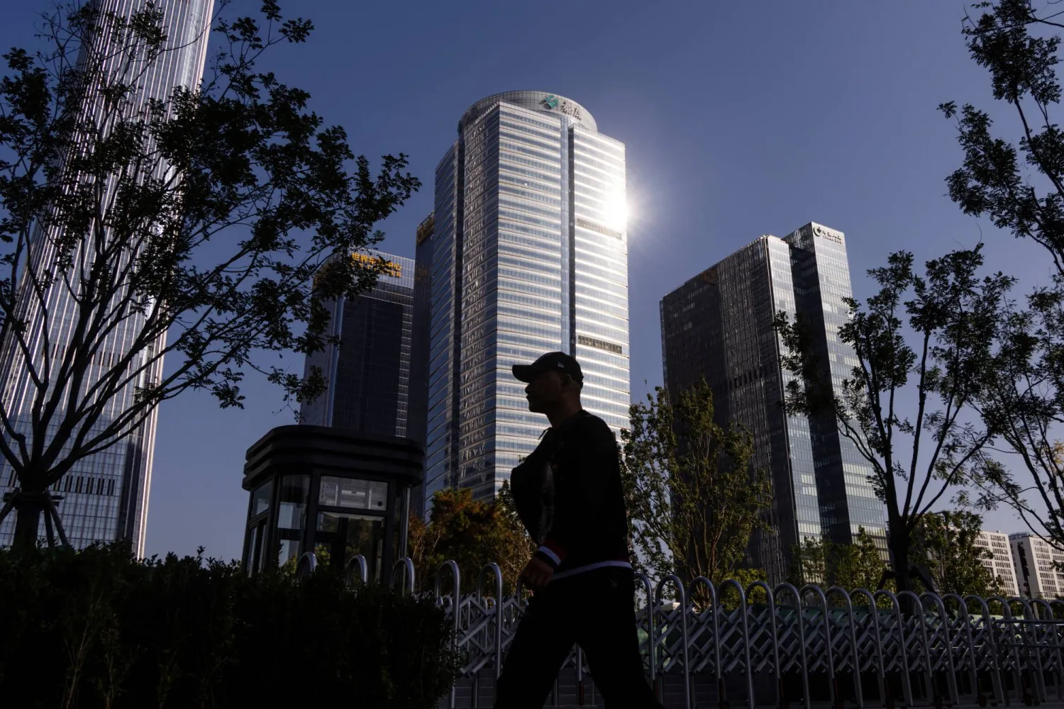A man walks past skyscrapers of the Central Business District (CBD) on a sunny day in Beijing, China, October 13, 2025. REUTERS/Maxim Shemetov