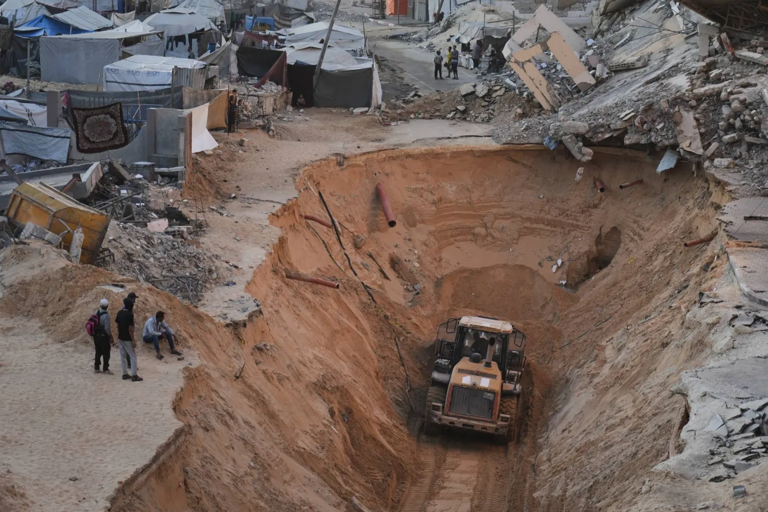 فلسطينيون يشاهدون أعضاء من حركة «حماس» وهم يبحثون عن جثث الرهائن في خان يونس جنوب قطاع غزة (أ.ب)