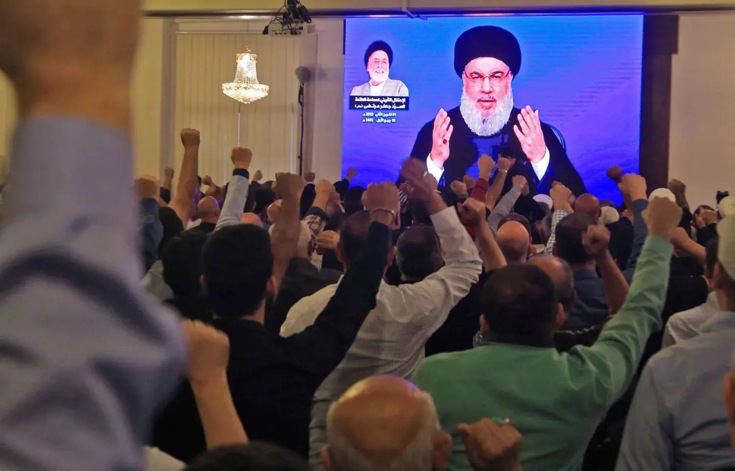 Beyrut'un güney banliyösündeki bir camide dev ekranda Hasan Nasrallah'ın konuşmasını izleyen Hizbullah destekçileri, Kasım 2019 (AFP)