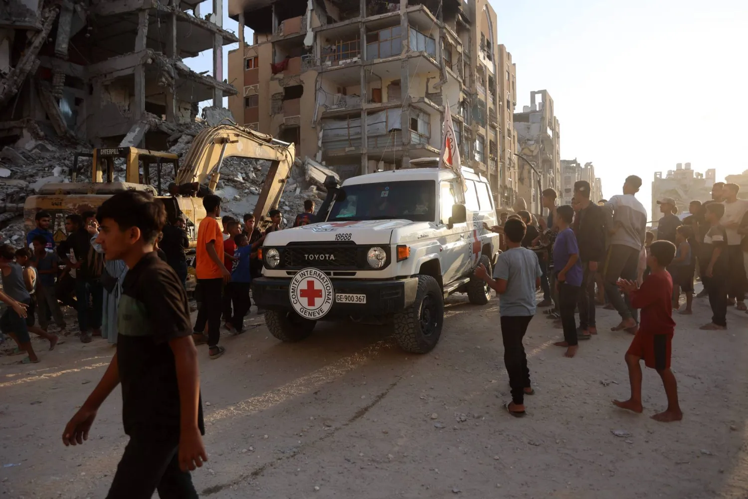 سيارة تتبع الصليب الأحمر تصل إلى موقع يشهد عمليات حفر للبحث عن جثث رهائن إسرائيليين في خان يونس (أ.ف.ب)