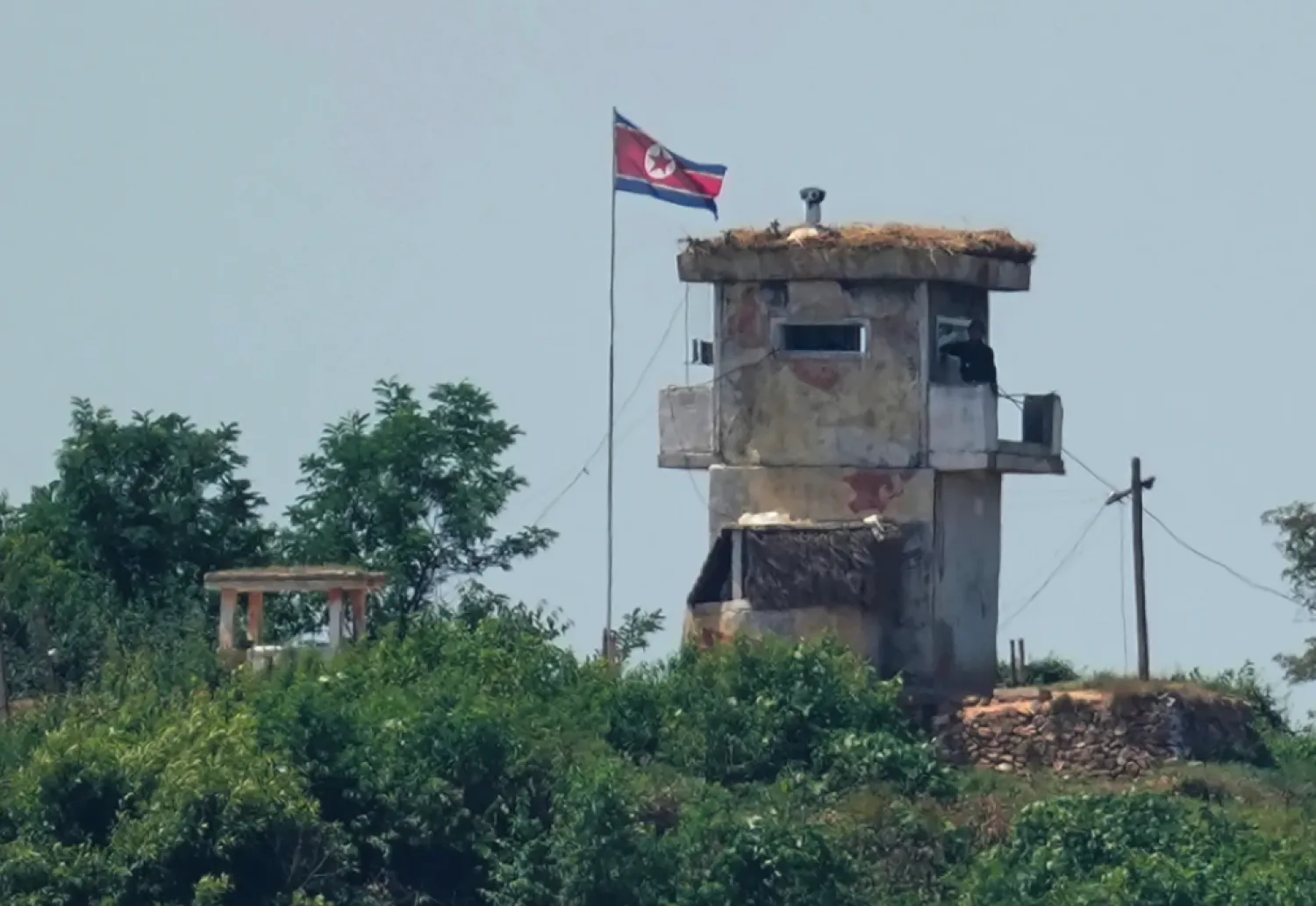 A soldier stands at a North Korean military guard post flying a national flag, seen from Paju, South Korea, June 26, 2024. (AP Photo/Lee Jin-man, File)