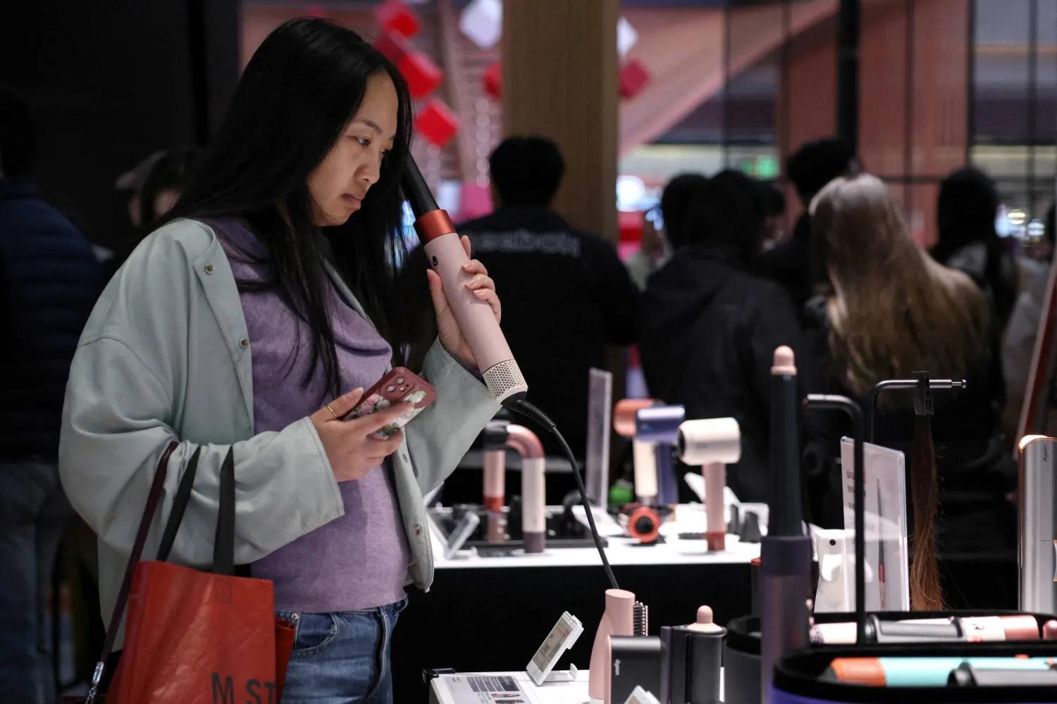 أمرأة تجرب مكواة فرد الشعر في مركز تجاري للأجهزة المنزلية في بكين (رويترز)