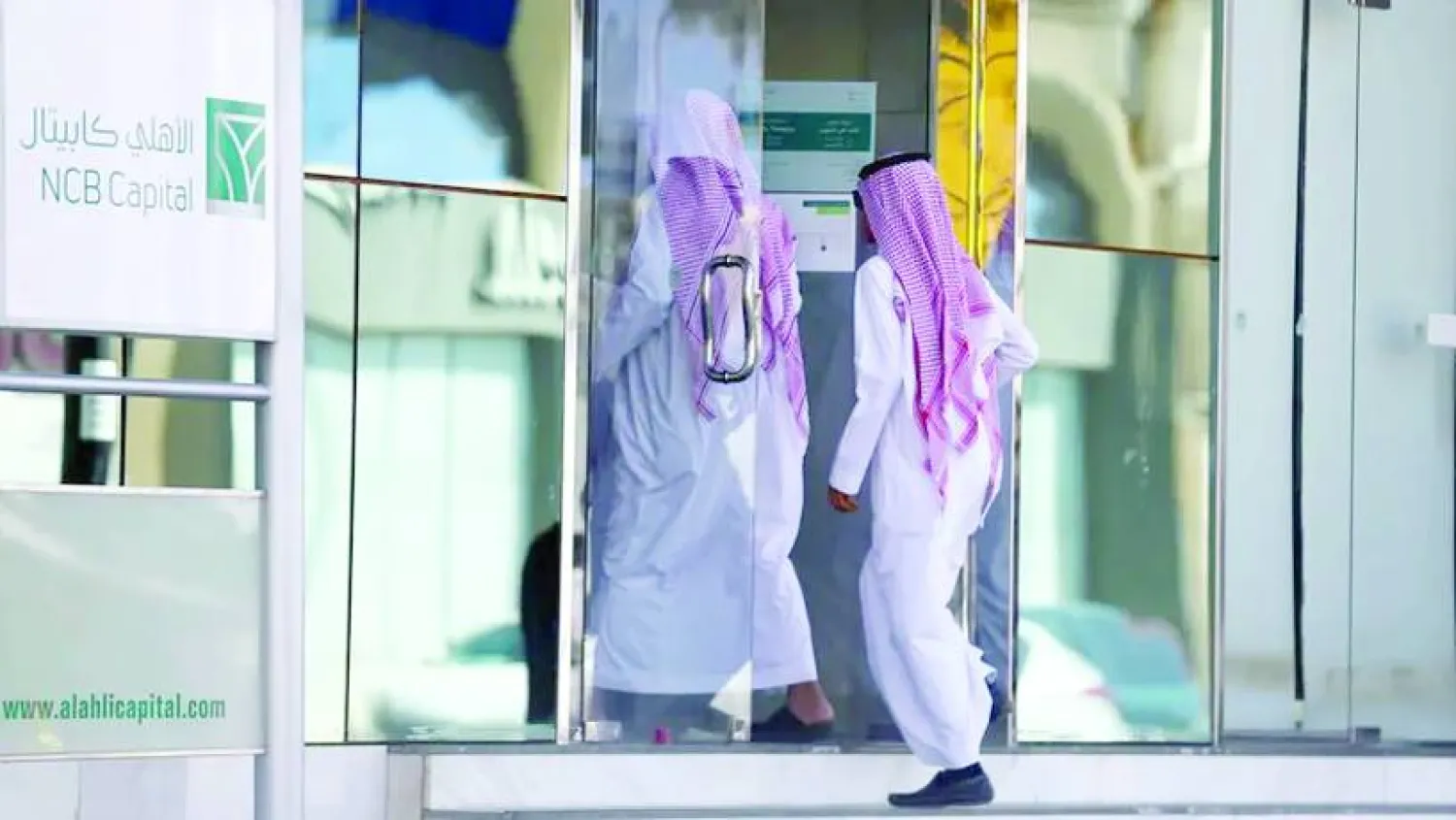 
أفراد يدخلون إلى أحد فروع «البنك الأهلي» في السعودية (رويترز)