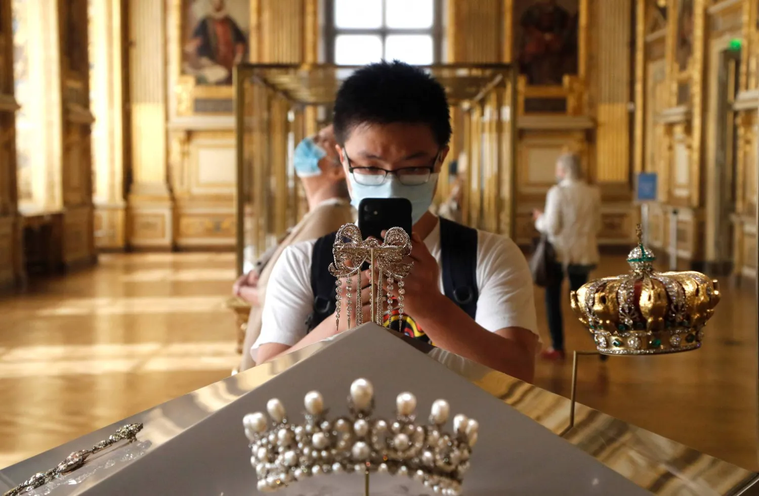 (FILES) A visitor wearing face mask takes a picture of Empress Eugenie's jewelry piece, at the Louvre Museum in Paris on July 6, 2020, on the museum' s reopening day. (Photo by FRANCOIS GUILLOT / AFP)