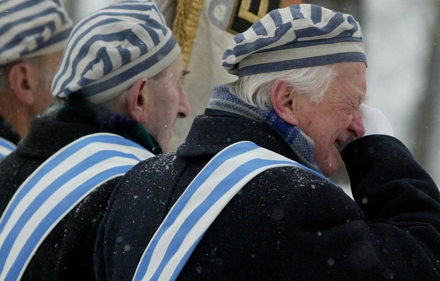 ناجٍ من معسكر اعتقال يمسح دمعة خلال مراسم أقيمت في معسكر الإبادة النازي السابق أوشفيتز بيركيناو ببولندا في 27 يناير 2005 (رويترز)