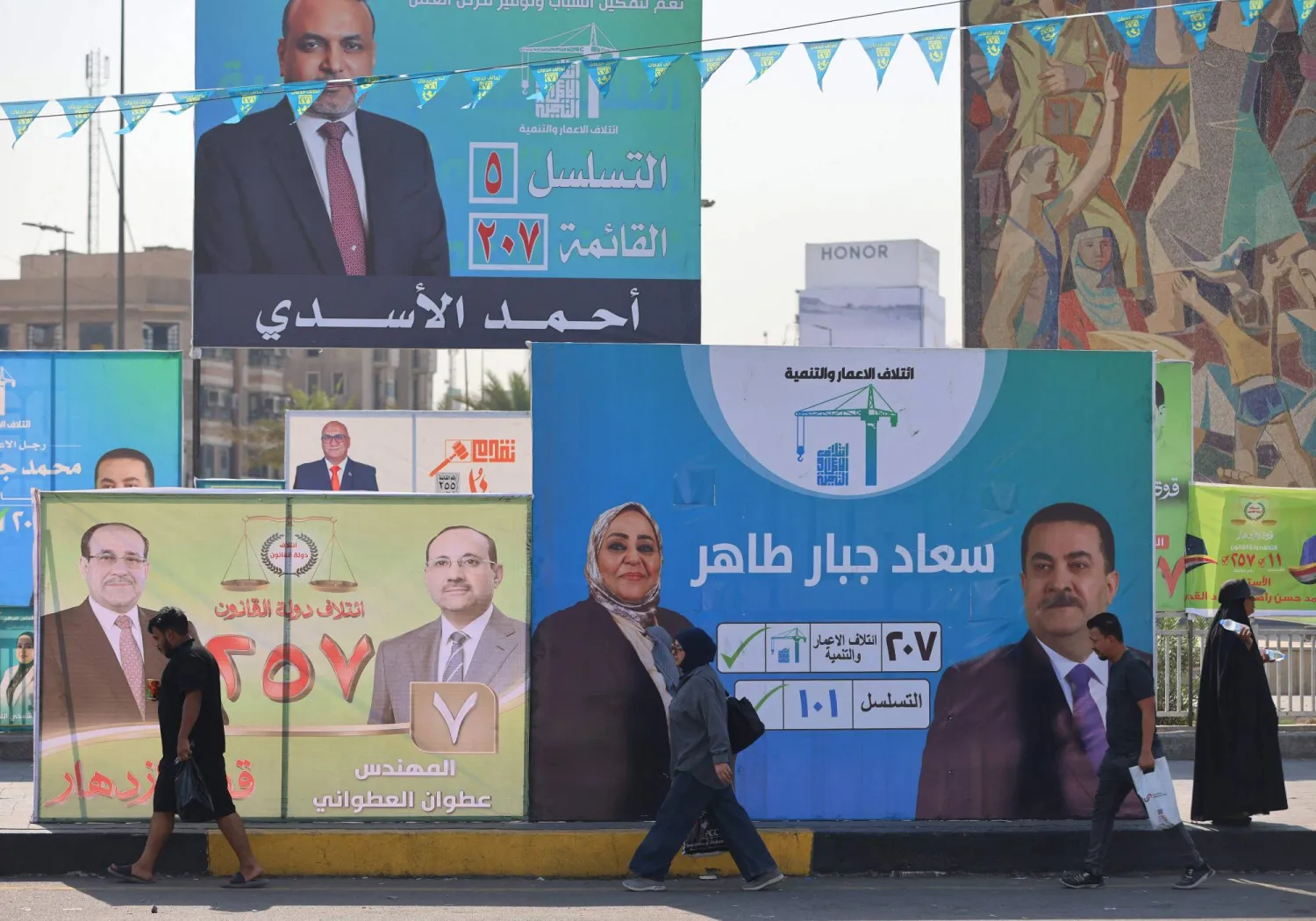 مارة يعبرون أمام لوحات انتخابية في وسط بغداد (أ.ف.ب)