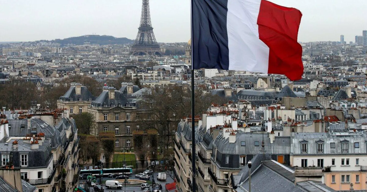 العلم الفرنسي يرفرف فوق أفق باريس مع برج إيفل (رويترز)