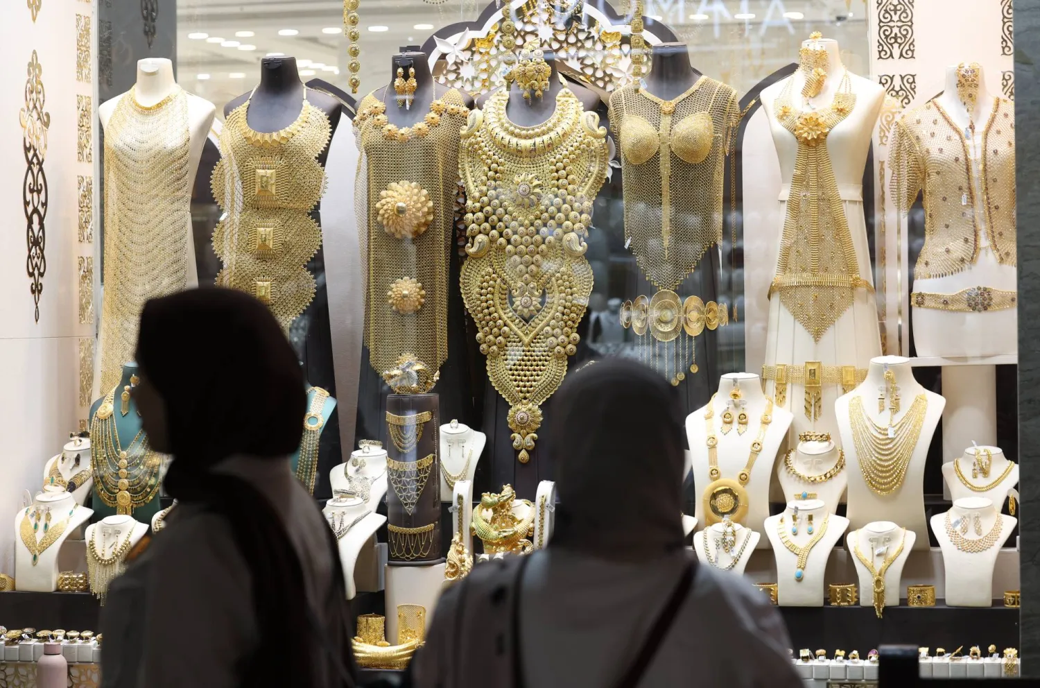 امرأتان تتفقدان قطعاً ذهبية في متجر للمجوهرات داخل سوق الذهب بدبي (إ.ب.أ)